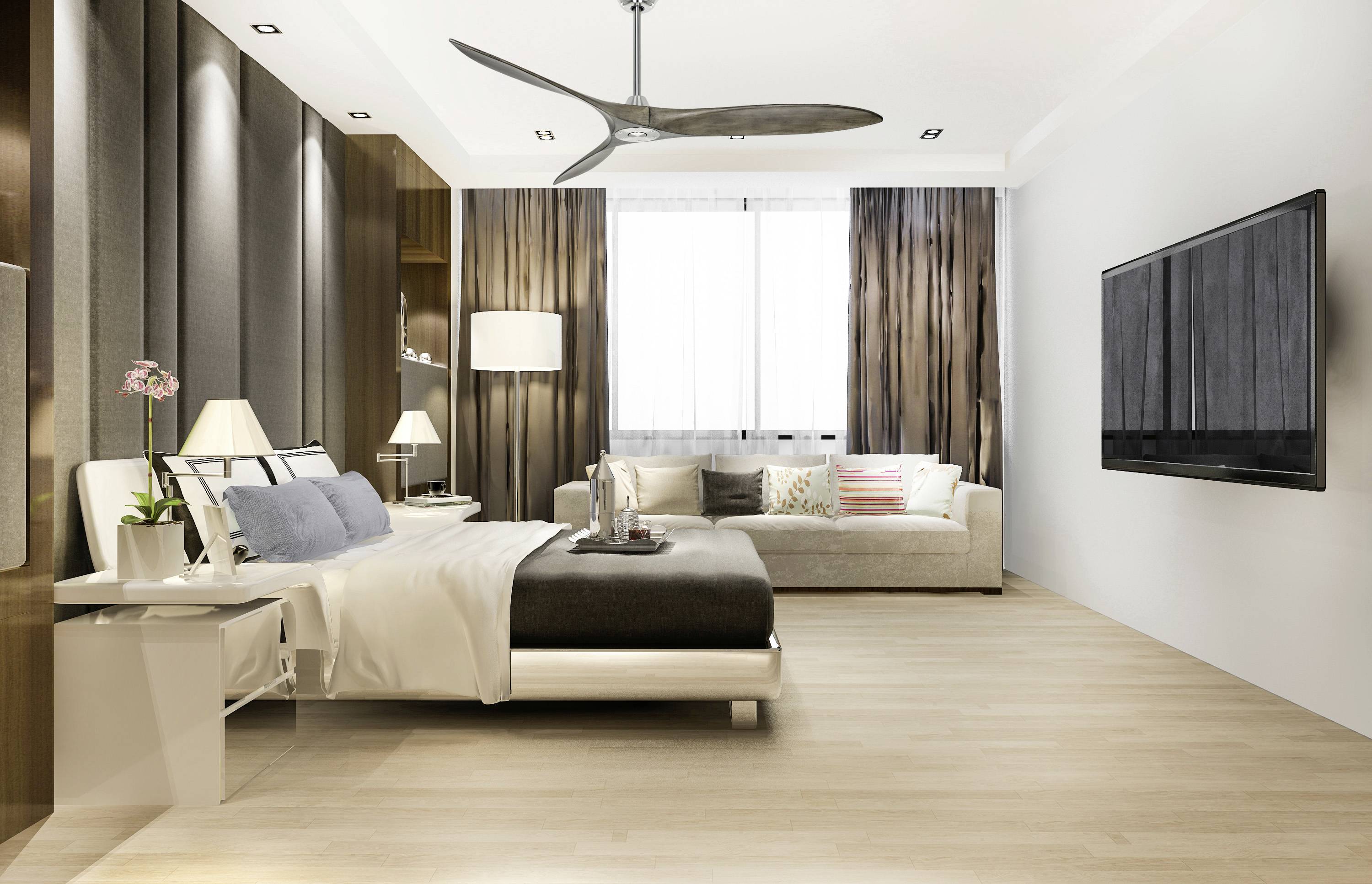 Moderne Schlafzimmeransicht mit Doppelbett, Sofa, großem Fernseher an der Wand und Deckenventilator; gut beleuchtet und stilvoll.