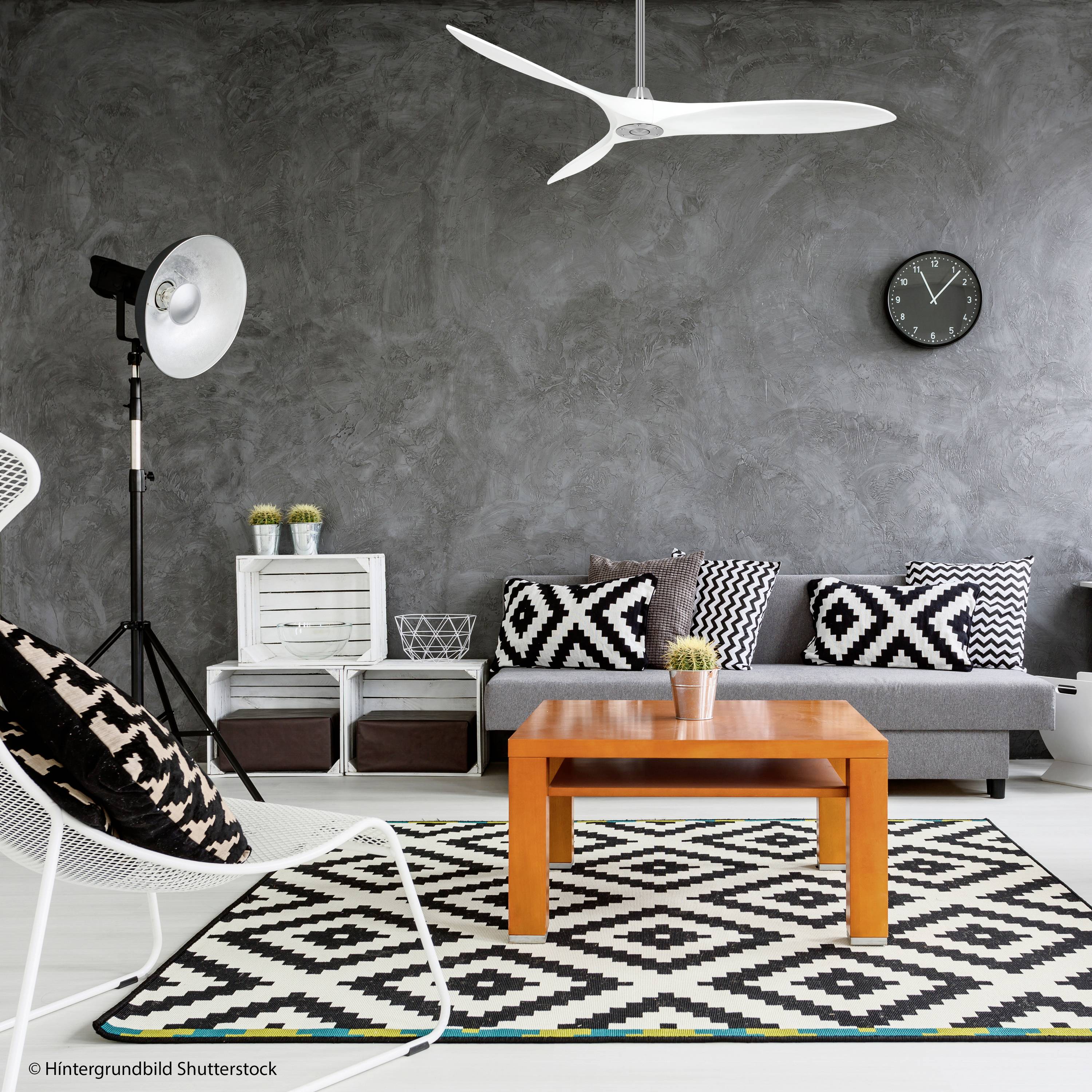 Modernes Wohnzimmer mit grau gestrichener Wand, Sofa mit gemusterten Kissen, orangefarbenem Couchtisch, und Teppich in Schwarz-Weiß-Muster.