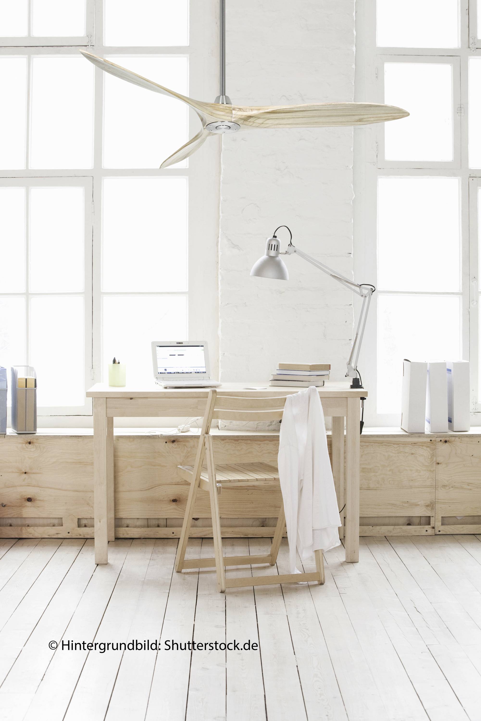 Ein heller, minimalistischer Arbeitsraum mit Holztisch und -stuhl, darauf ein Laptop und Lampe. Große Fenster im Hintergrund lassen viel Licht herein.