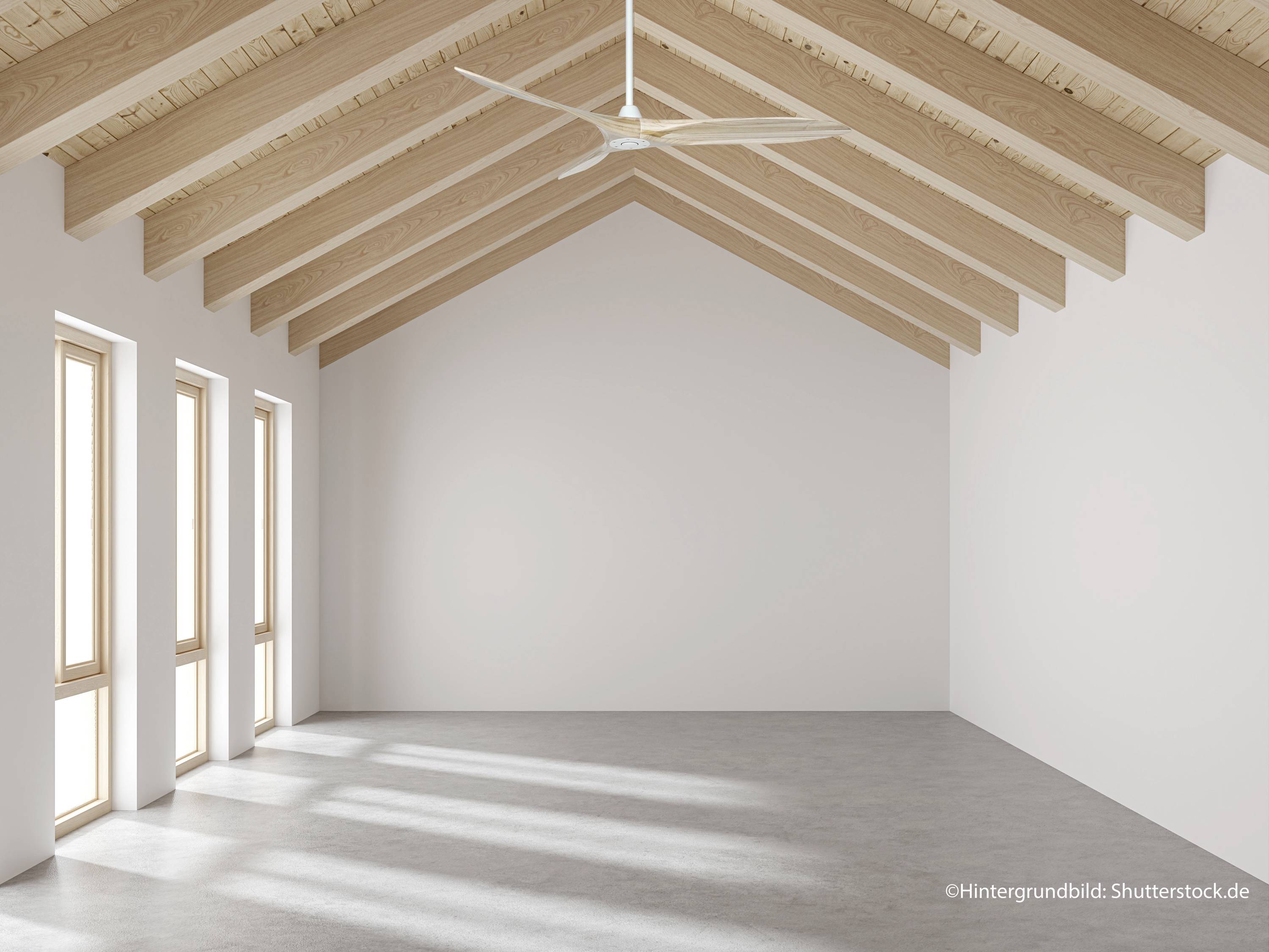 Ein leerer Raum mit Holzdecke und großen Fenstern, die natürliches Licht einlassen. Ein weißer Deckenventilator hängt von der Decke.