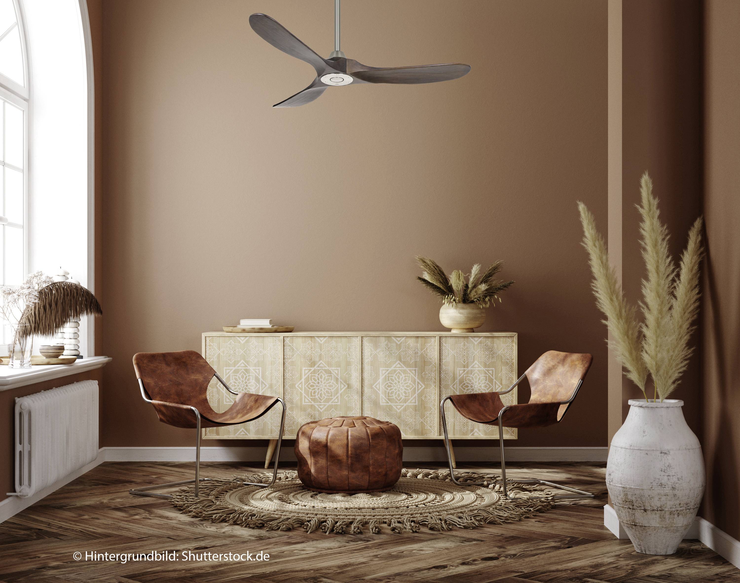 Ein stilvoller Raum mit zwei braunen Stühlen, einem runden Hocker, einem dekorativen Teppich und einem Holztisch. Wandfarbe in warmem Braun.