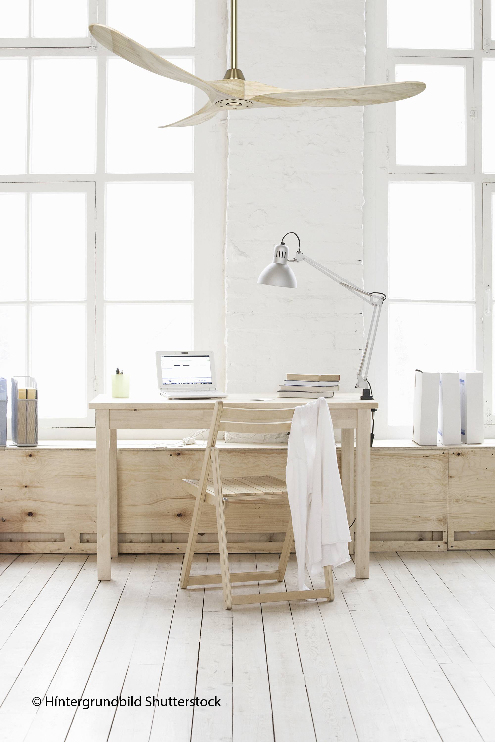 Ein minimalistisch eingerichteter Arbeitsplatz mit einem Holztisch, Laptop, Lampe, Holzstuhl und großen Fenstern im Hintergrund.