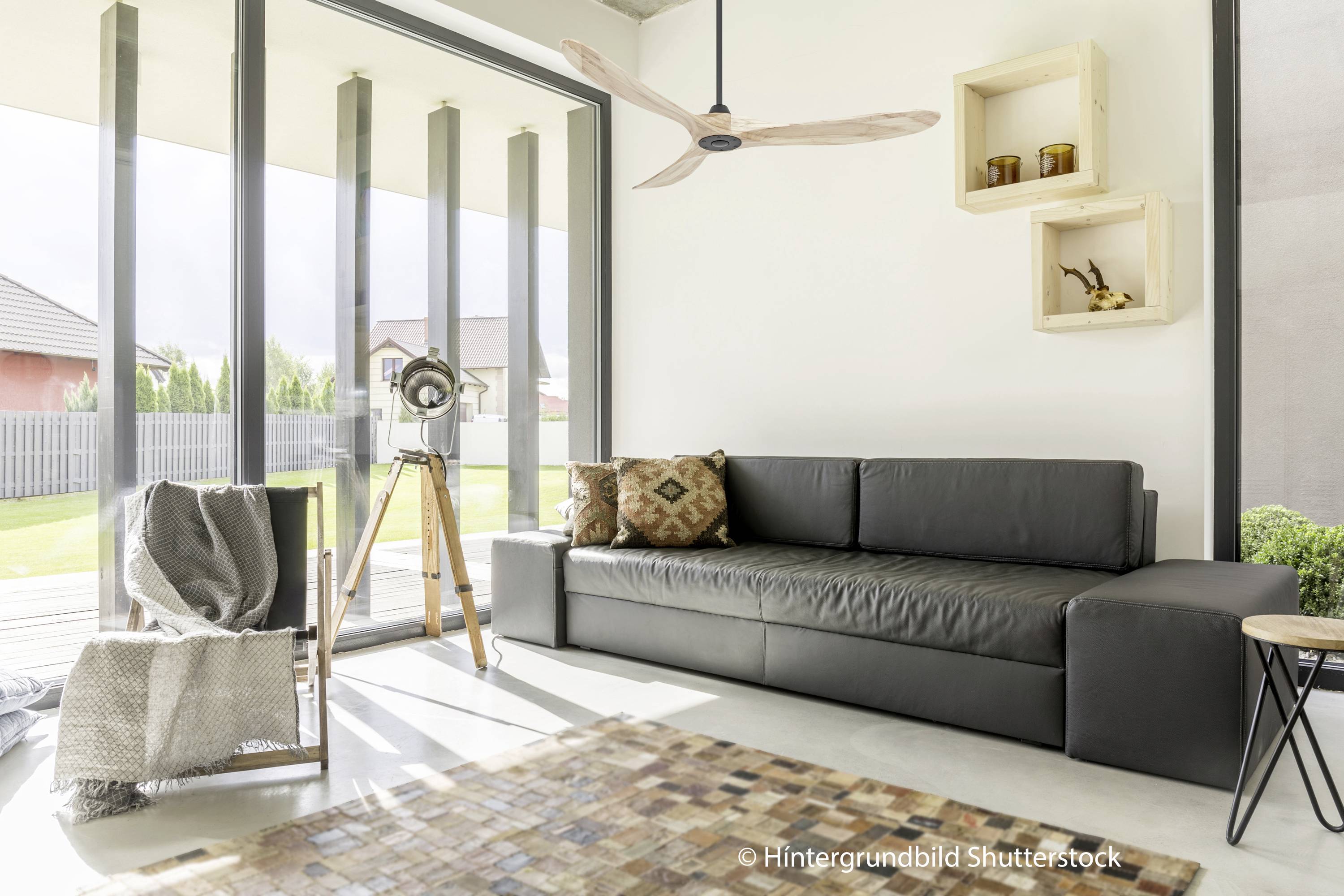 Wohnzimmer mit schwarzem Ledersofa, Holzboden, großem Fenster, Stehlampe und Holzregalen, die moderne Eleganz ausstrahlen.