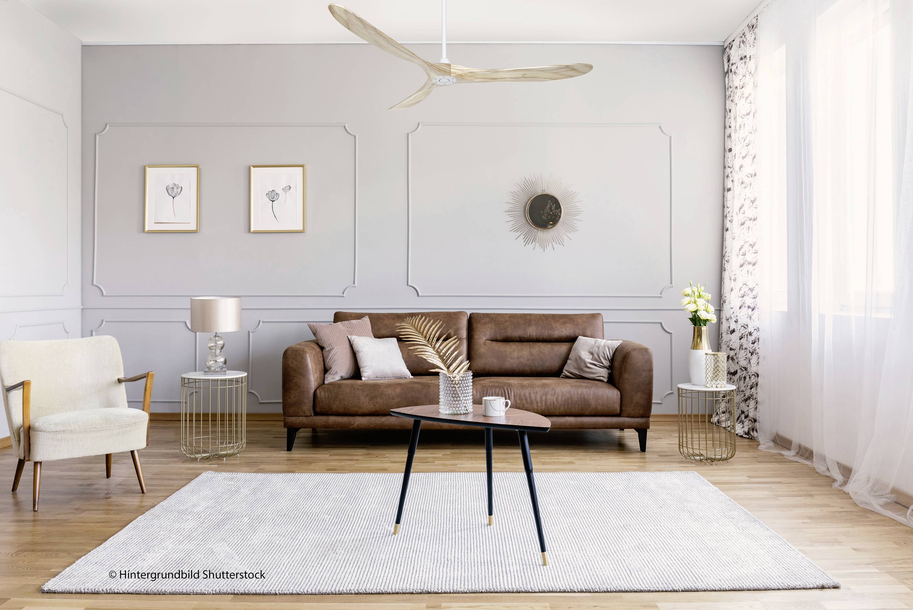 Gemütliches Wohnzimmer mit Ledersofa, hellem Teppich und dekorativen Elementen, wie einem Sonnenwandbild und Pflanzen.