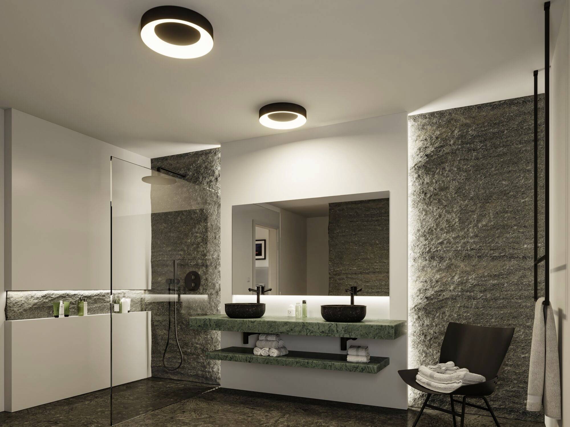 Modernes Badezimmer mit zwei Waschbecken, großer Spiegel und Regendusche. Steinverkleidete Wände und indirekte Beleuchtung sorgen für Eleganz.