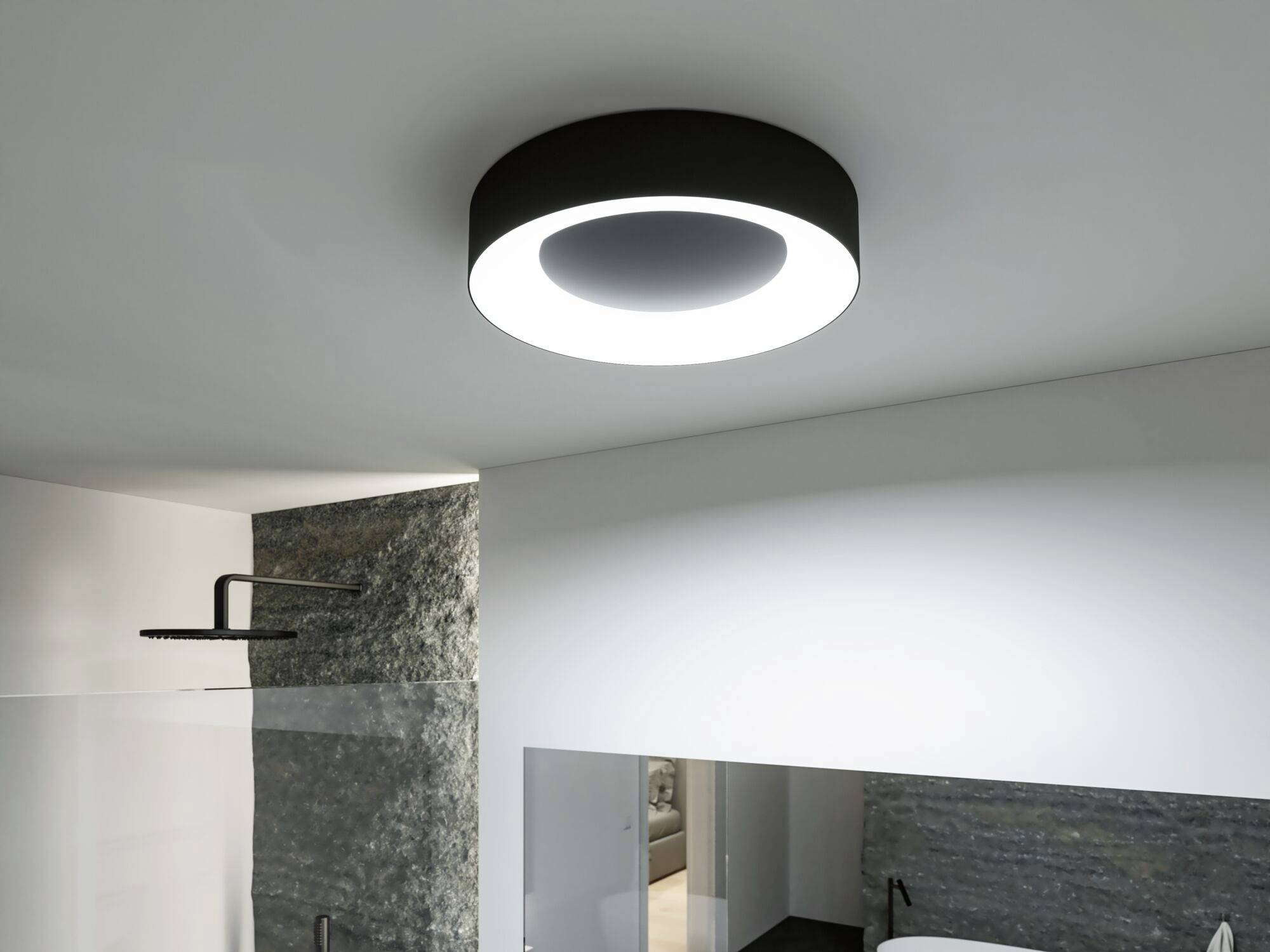 Eine moderne runde Deckenleuchte leuchtet einen Badezimmerbereich aus, der eine Regendusche und eine Steinwand umfasst.