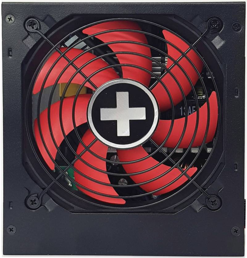 Ein Computer-Netzteil mit einem Lüfter mit roten Flügeln und einem weißen Kreuz in der Mitte, geschützt durch ein Gitter.
