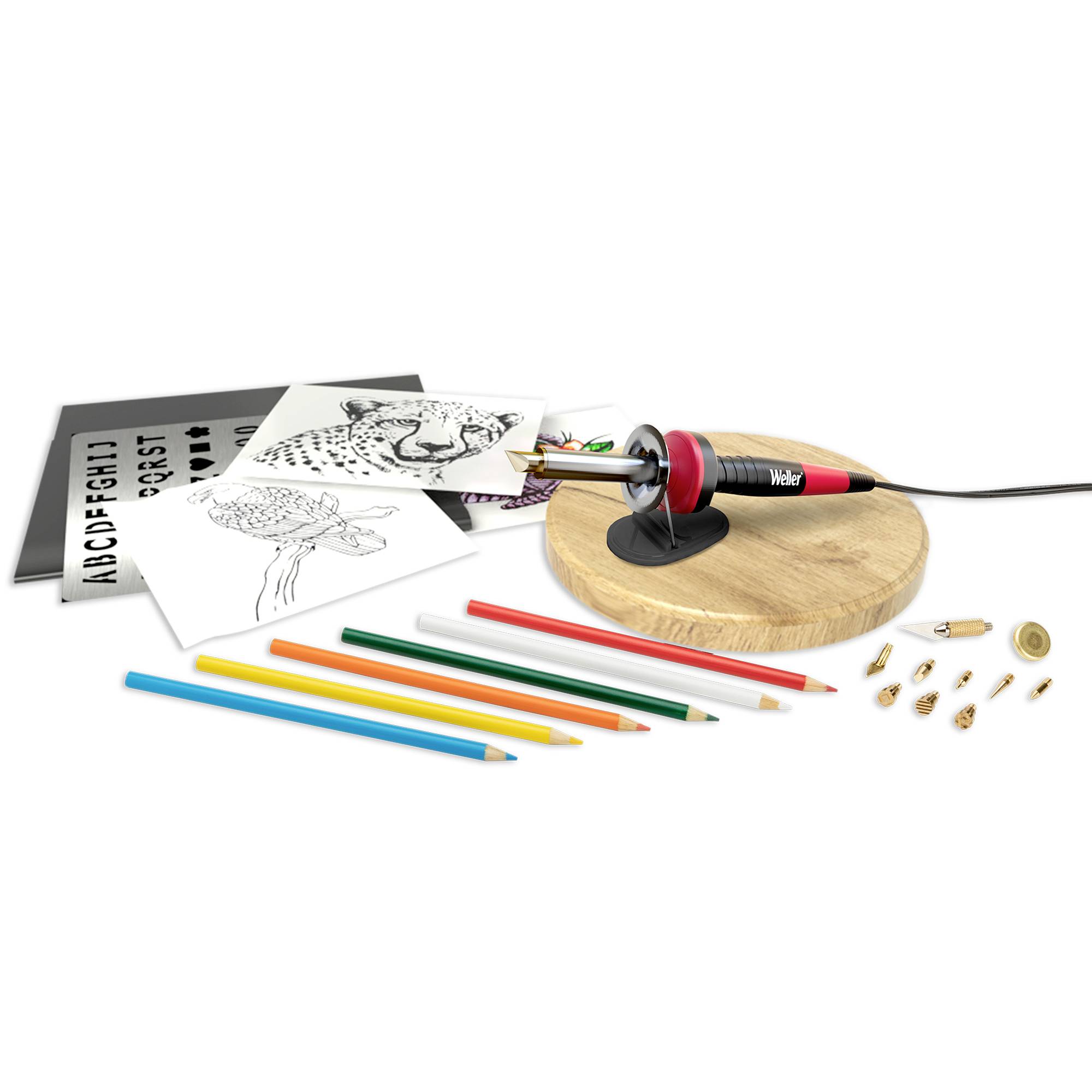 Ein Brennkolben mit Aufsätzen liegt auf einem Holzschneider, daneben Buntstifte und Vorlagen mit einem gepunkteten Tiermotiv und Buchstaben.