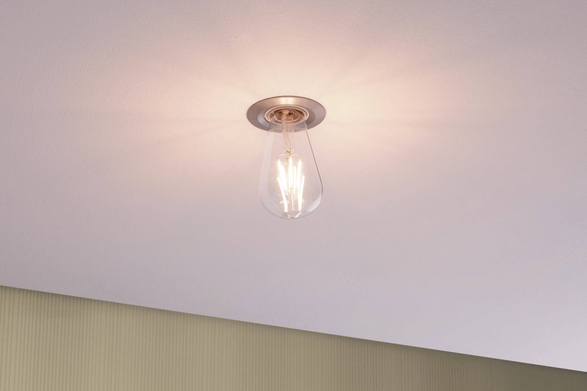 Eine an der Decke montierte Glühbirne mit warmem, diffusem Licht, das den Raum sanft beleuchtet.