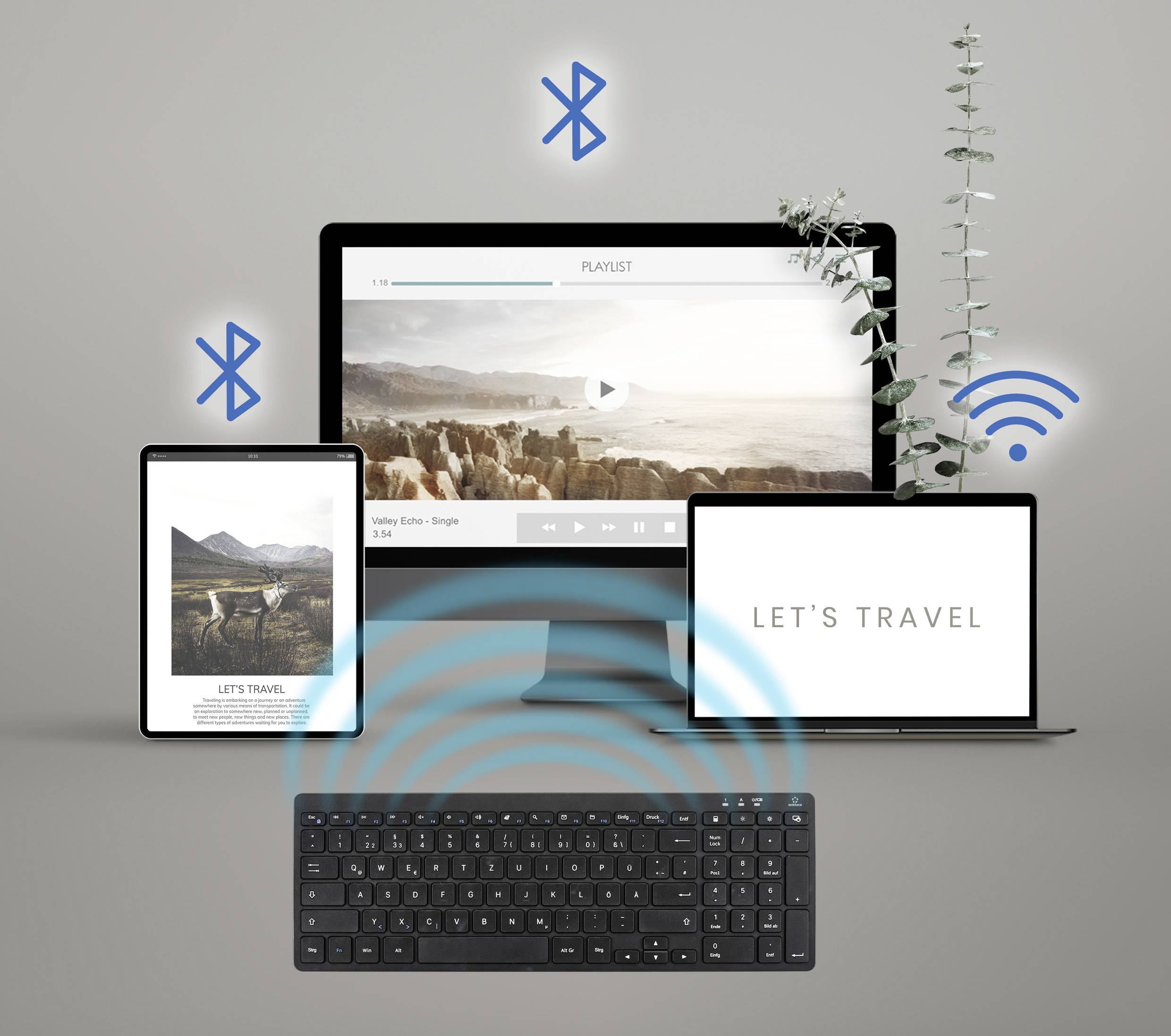 Digitalgeräte auf einem Tisch: ein Tablet mit Naturfoto, ein Monitor mit Landschaftsvideo, ein Laptop mit 'LET'S TRAVEL'-Text und eine Tastatur mit kabellosen Verbindungen.