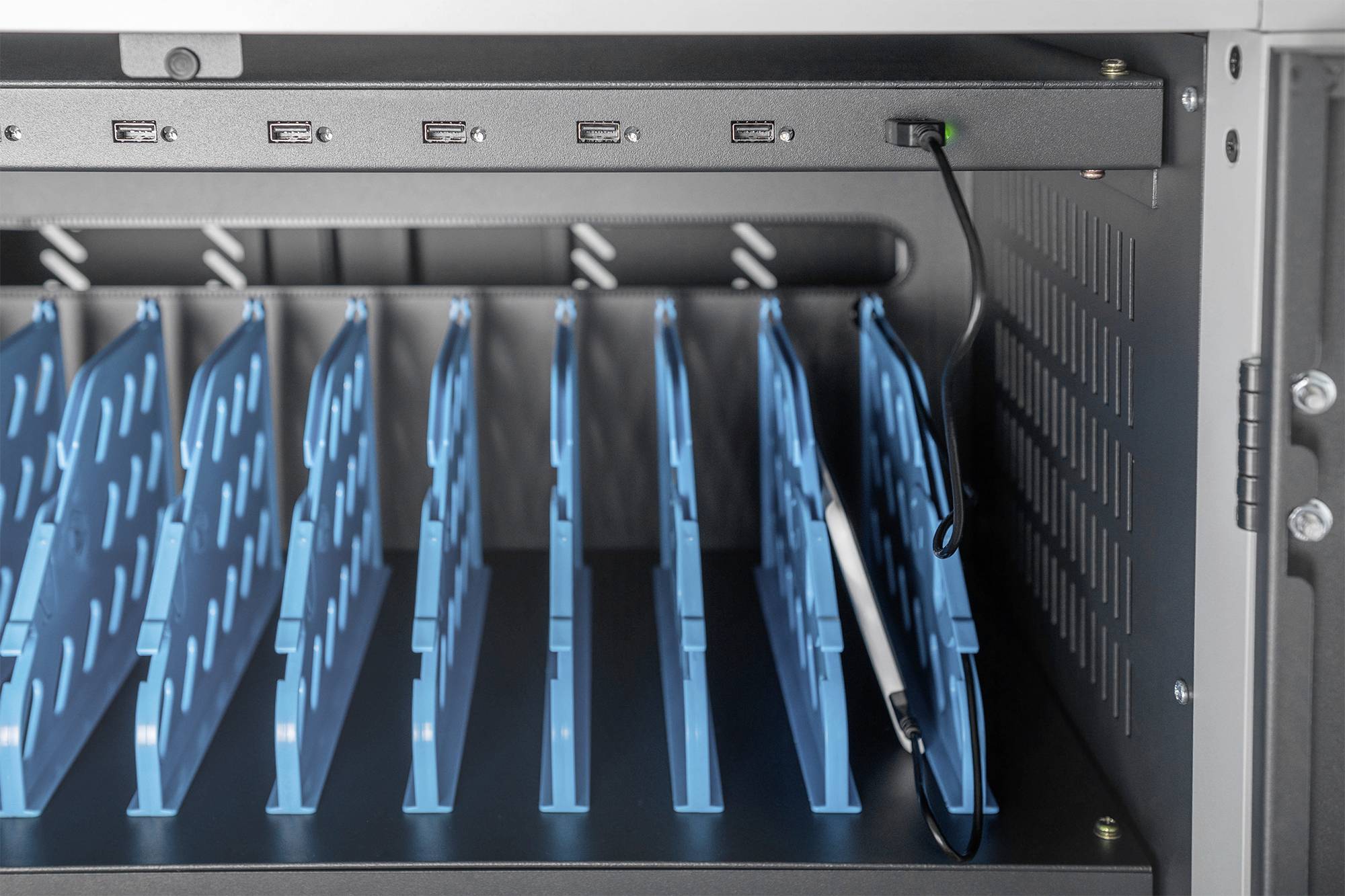 Innenansicht eines Aufbewahrungs- oder Ladenschranks mit blauen Trennfächern für Tablets oder Laptops und USB-Anschlüssen.