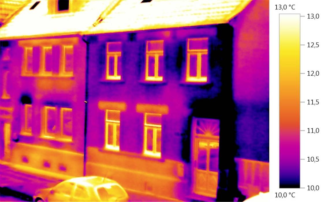 Thermografiebild eines Hauses zeigt Wärmeverlust an Fenstern und Türen. Farbskala rechts visualisiert Temperatur von 10 bis 13 °C.