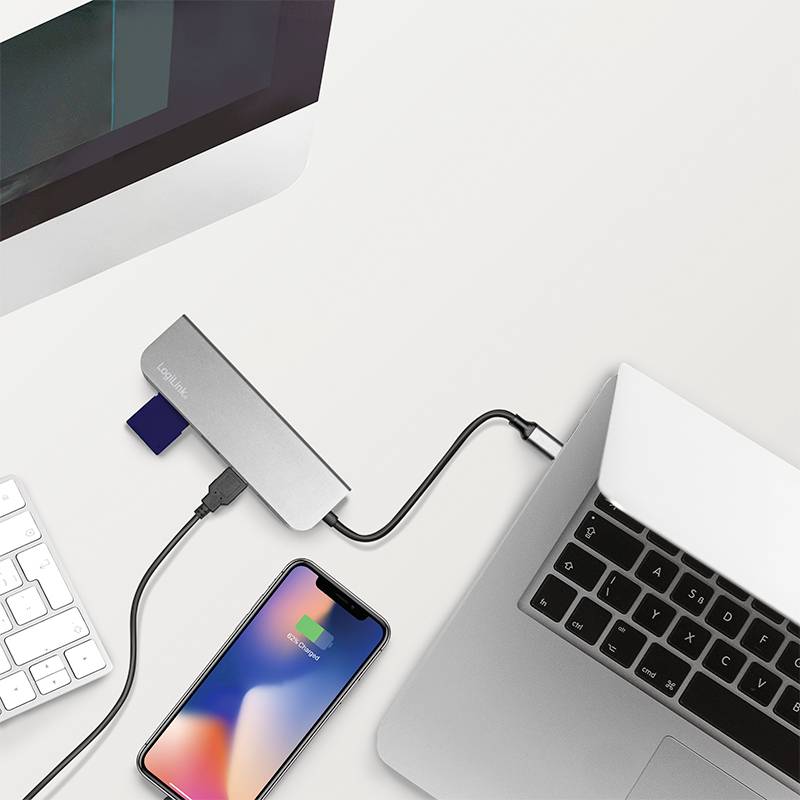 Ein Laptop und ein Smartphone sind mit einem USB-Hub verbunden, der auch eine Speicherkartenverbindung zeigt. Technologie-Setup.