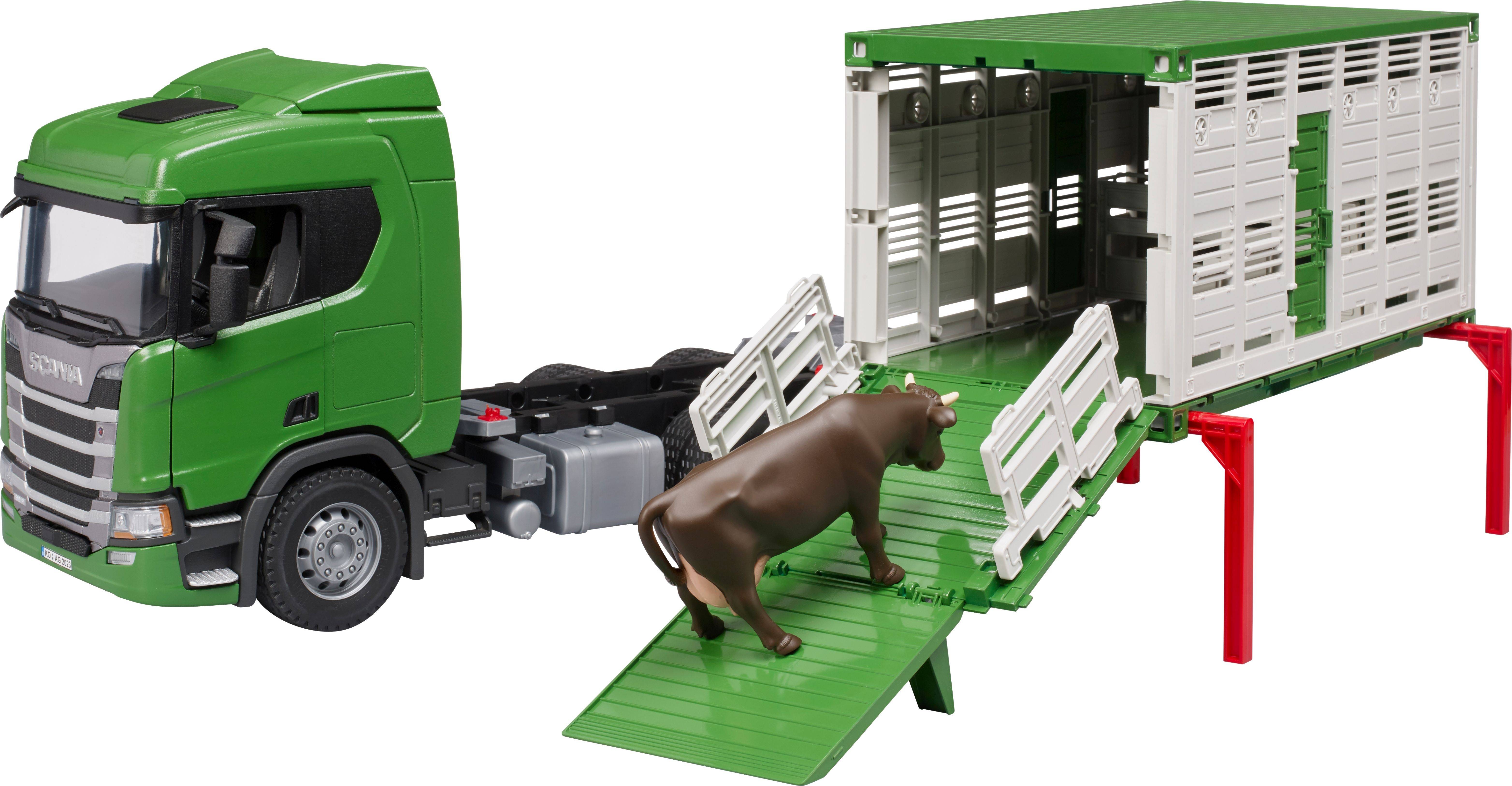 Ein grüner Spielzeuglastwagen mit Tieranhänger zeigt eine Kuh, die eine Rampe hinaufgeht. Der Anhänger ist zum Beladen geöffnet.