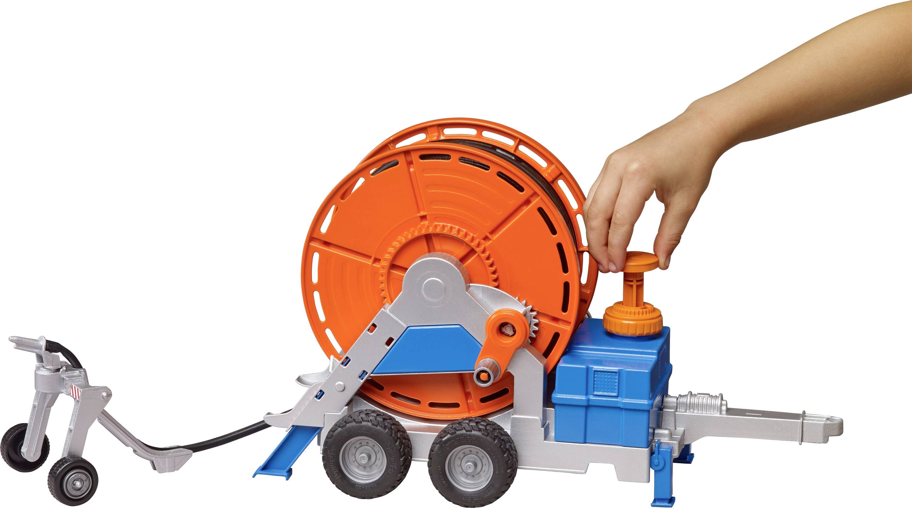 Ein Kind bedient ein Spielzeug, das eine orangefarbene Kabeltrommel auf einem blauen Fahrgestell mit Rädern darstellt.