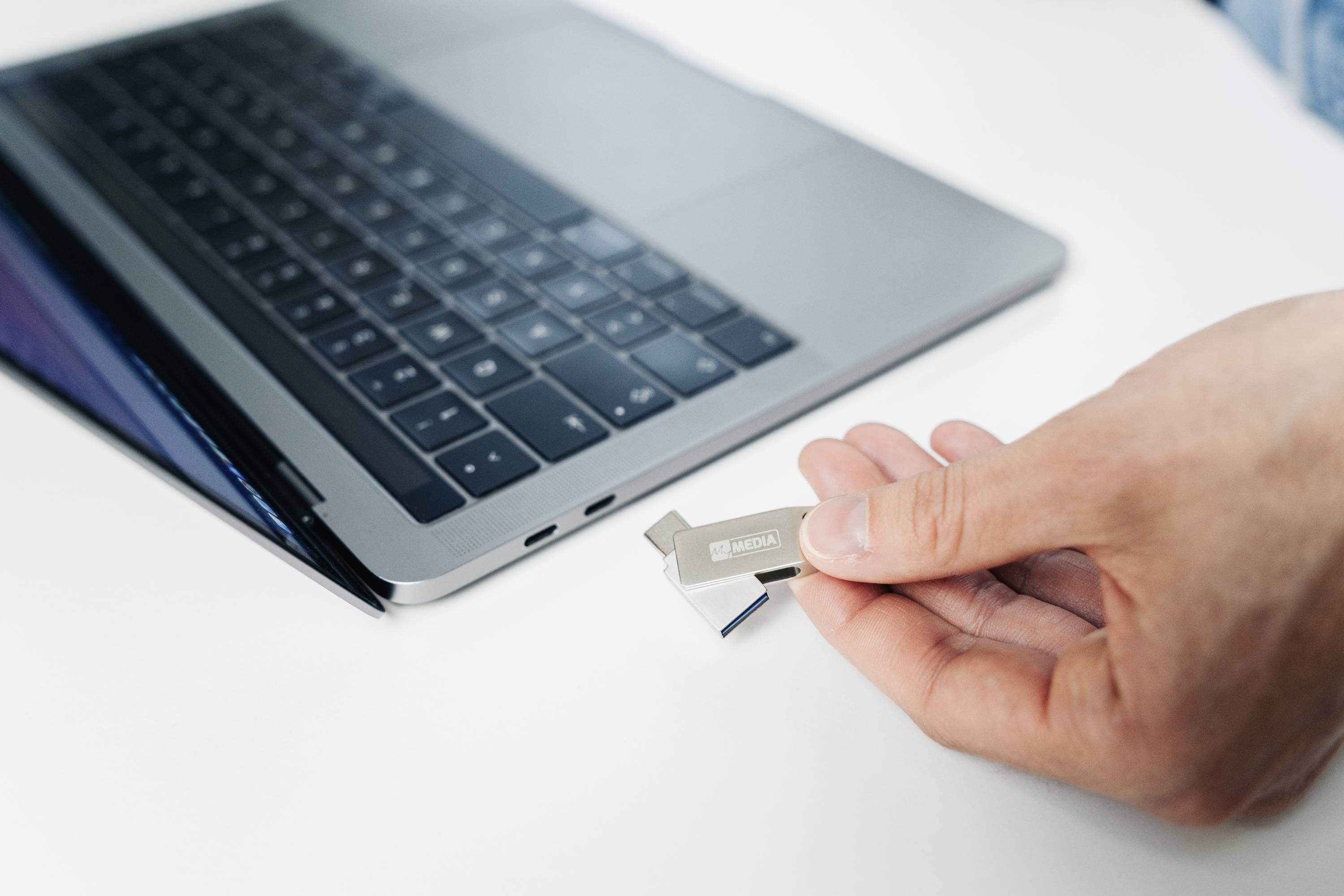 Eine Hand steckt einen USB-Stick in einen Laptop. Der Fokus liegt auf der Verbindung von Gerät und Speicherstick.