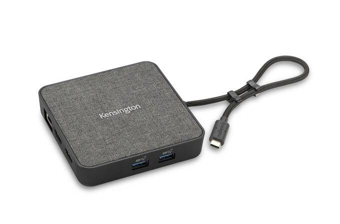 Ein quadratischer USB-C-Hub von Kensington mit Stoffoberfläche, mehreren Anschlüssen und einem kurzen Anschlusskabel.
