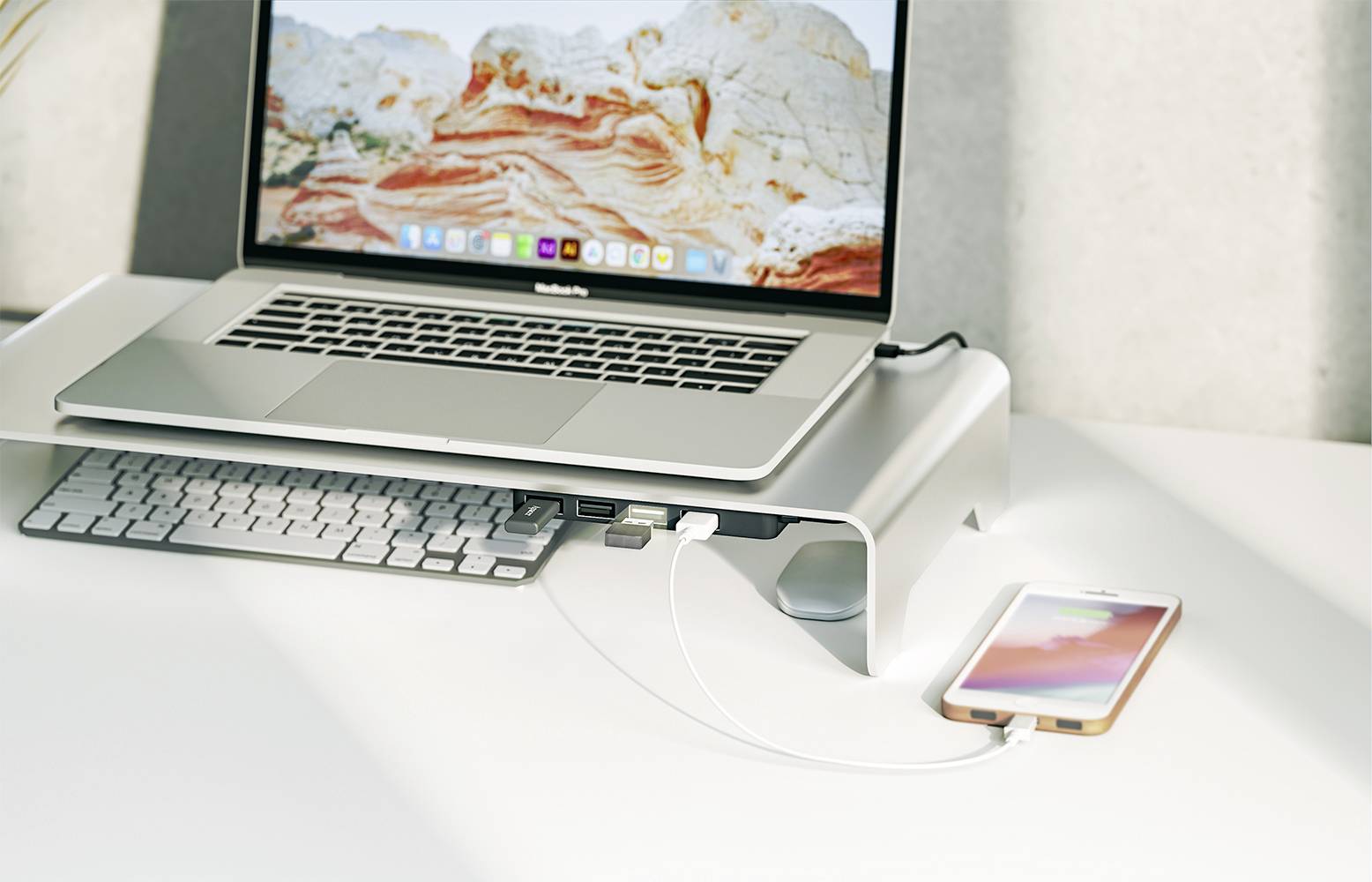 Ein Laptop auf einem Ständer, verbunden mit einem Smartphone. Darunter eine Tastatur. Der Bildschirm zeigt eine Landschaft.