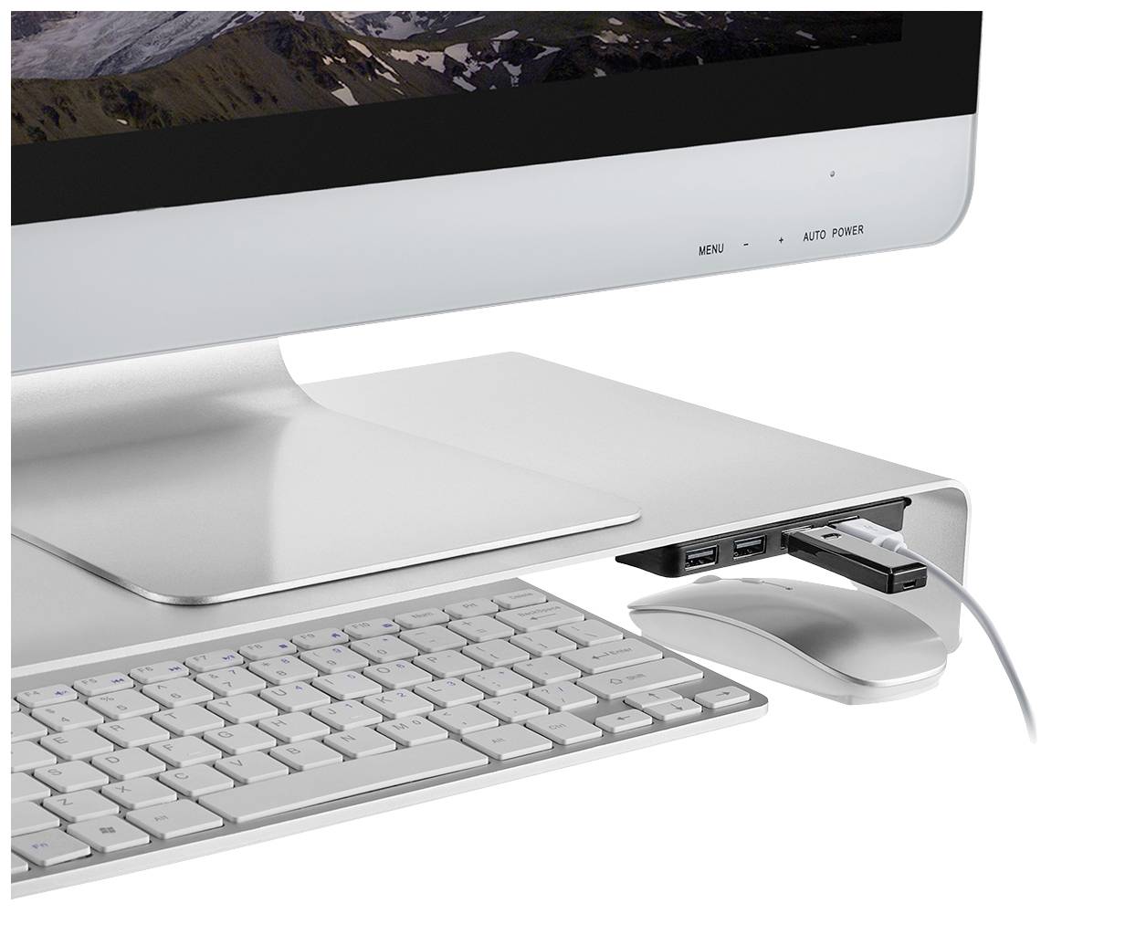 Ein Computerbildschirm mit einer erhöhten Aluminiumhaube, darunter eine Tastatur und Maus. An der Haube sind USB-Geräte angeschlossen.