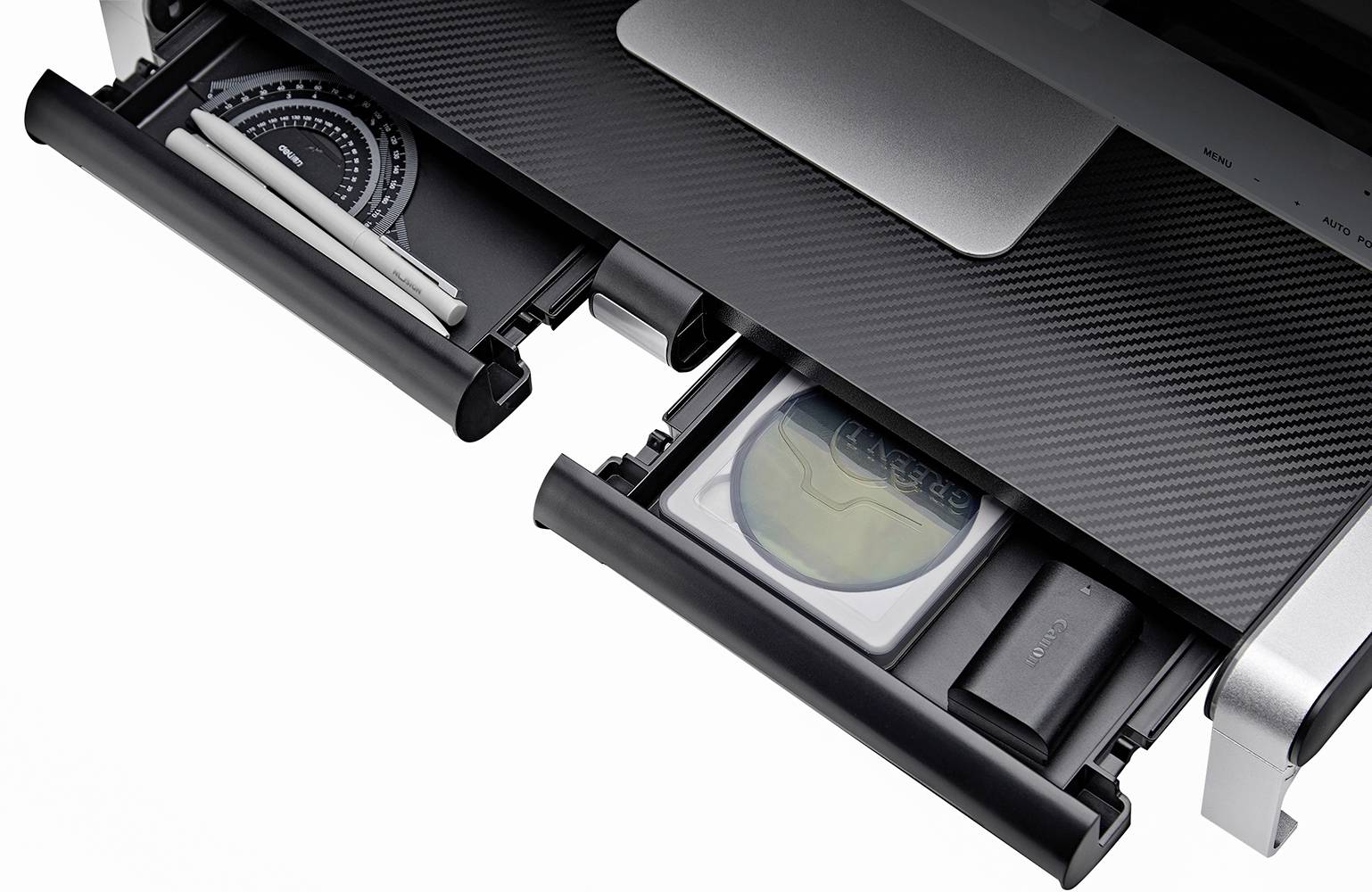 Zwei geöffnete Schubladen eines Schreibtischs, links mit Stiften und einem Geometrie-Dreieck, rechts mit einem beschrifteten Umschlag und einem schwarzen Gerät.