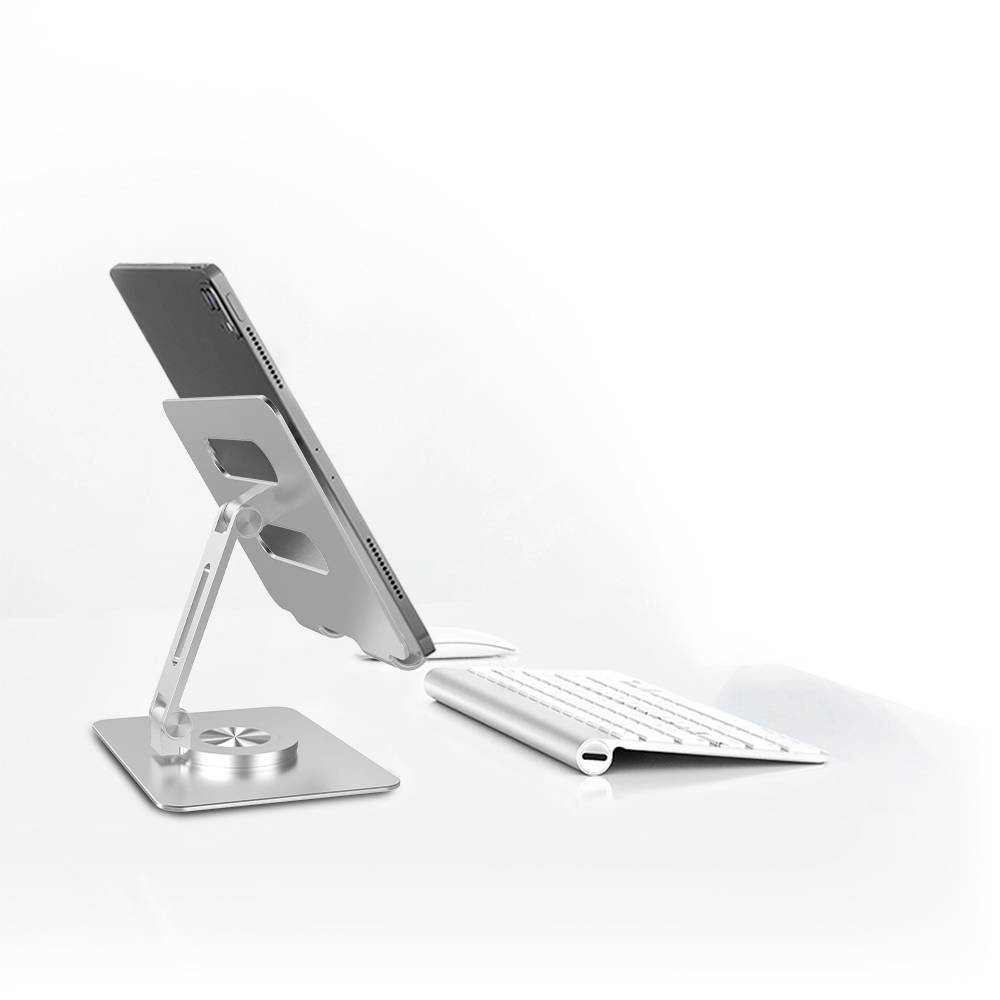 Ein Laptop steht auf einem verstellbaren, silbernen Ständer neben einer weißen, kabellosen Tastatur auf einem weißen Hintergrund.