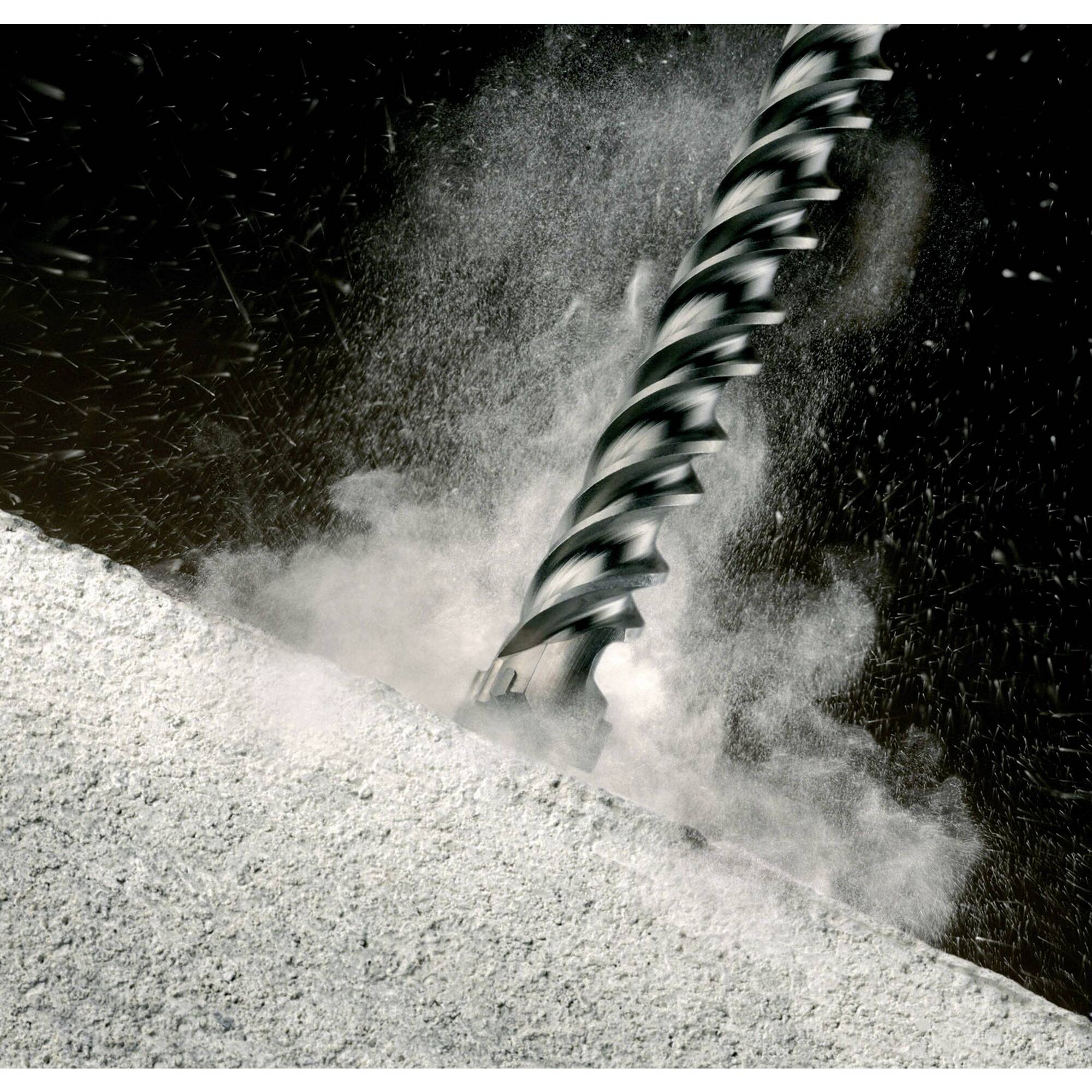 Bohrer durchdringt Beton, Staubwolke entsteht.