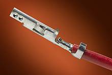 Ein Metallstecker ist an ein rotes Kabel angeschlossen. Der Hintergrund ist unscharf in Braun- und Orangetönen gehalten.