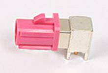 Ein pinker Koaxialstecker mit rechteckigem Metallgehäuse und zwei silbernen Kontakten, typisch für elektronische Verbindungen.