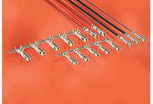 Reihe von Metallklemmen auf einer orangen Oberfläche, verbunden mit bunten Drähten oben; elektrische Anschlusskomponenten.