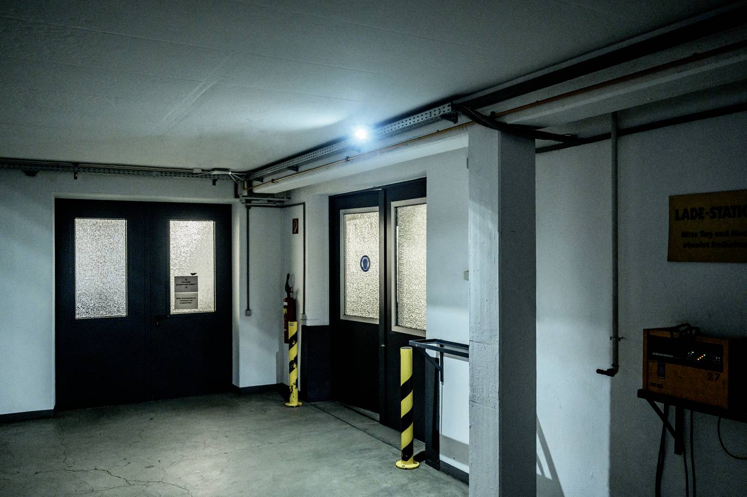 Ein Parkhaus mit geschlossenen Türen, beleuchtet durch ein blaues Licht. Ein 