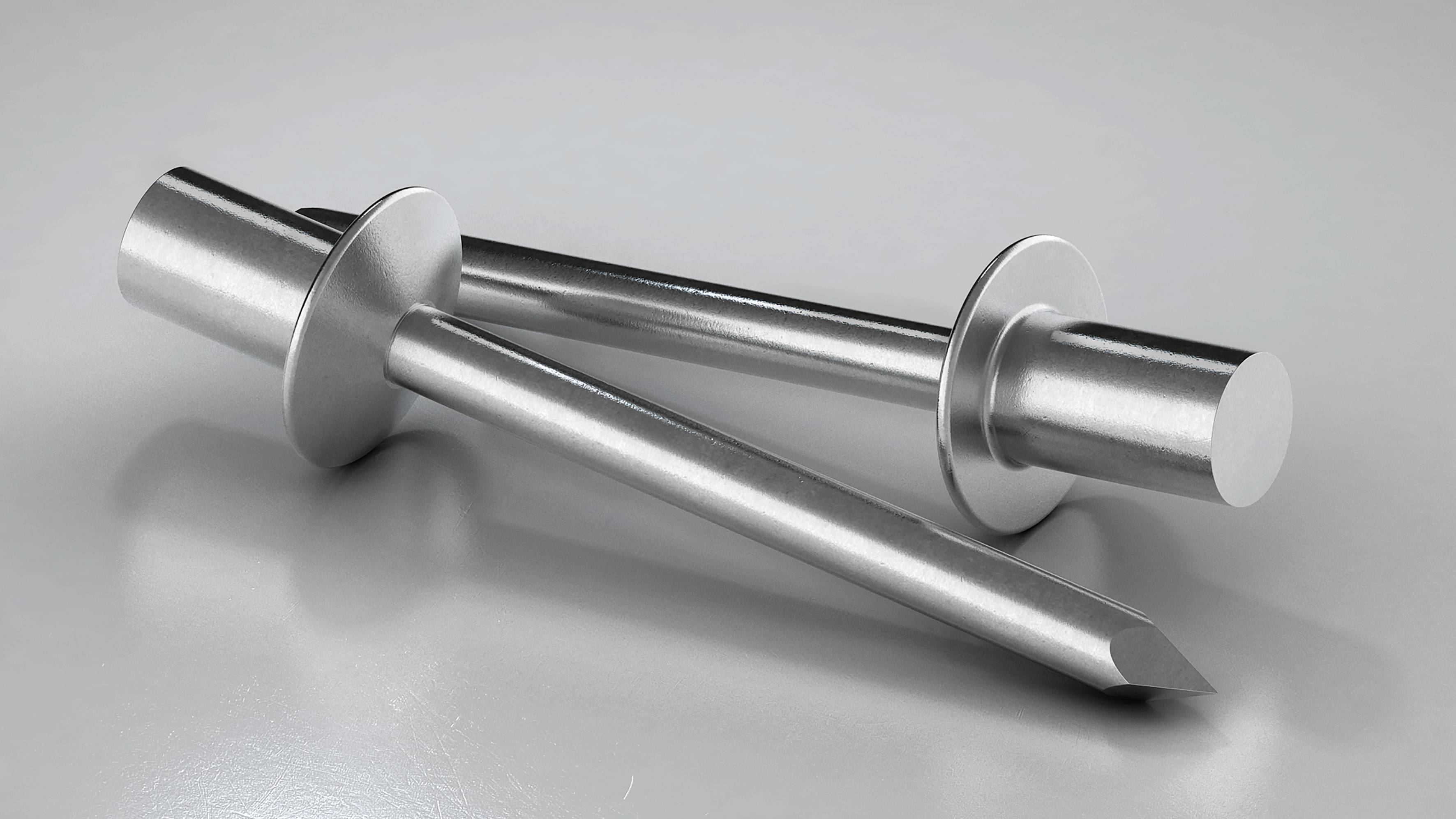 Zwei glänzende Metallmeißel auf einer grauen Oberfläche. Ein Meißel hat eine flache Spitze, der andere eine schräg abgeschnittene Spitze.