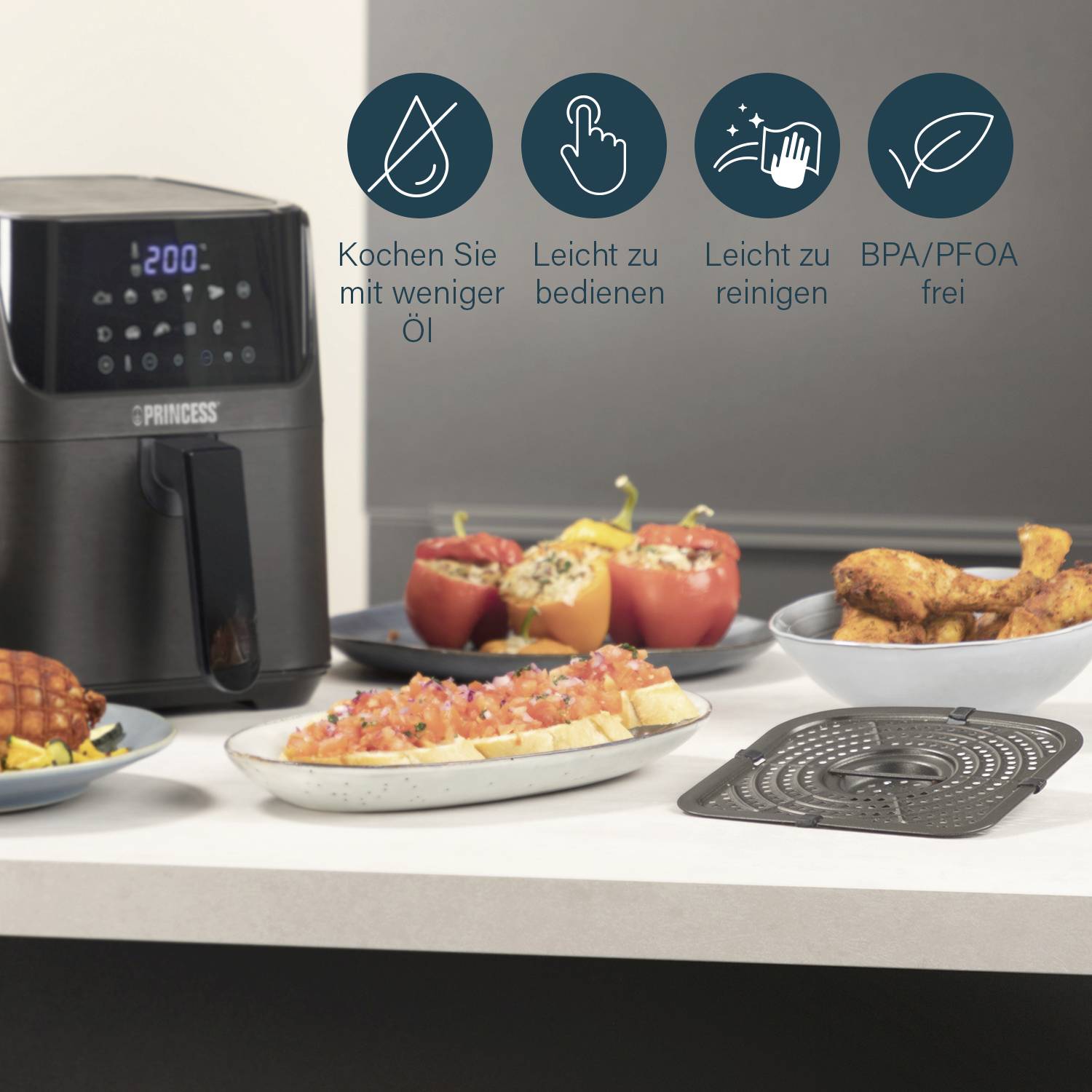 Luftfritteuse auf einem Küchentresen, umgeben von Tellern mit Fingerfood und Gemüse. Icons zeigen Vorteile: weniger Öl, leicht zu reinigen.