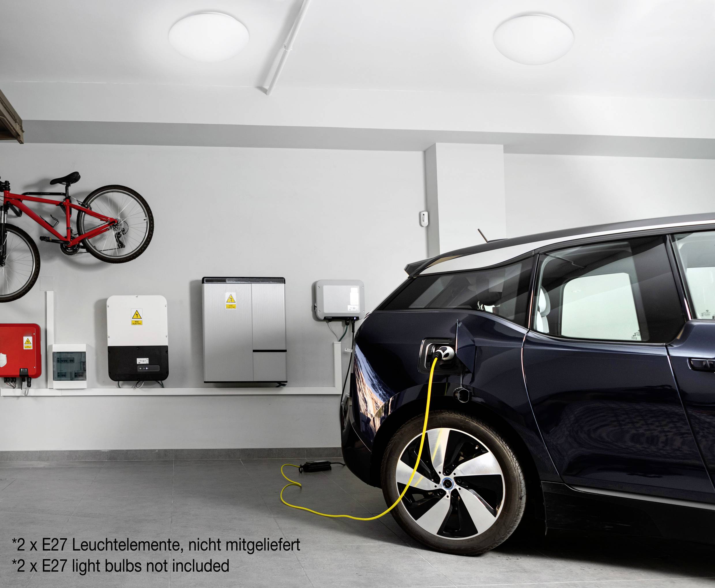 Ein Elektroauto wird in einer modernen Garage aufgeladen. An der Wand sind mehrere Geräte und ein Fahrrad befestigt.