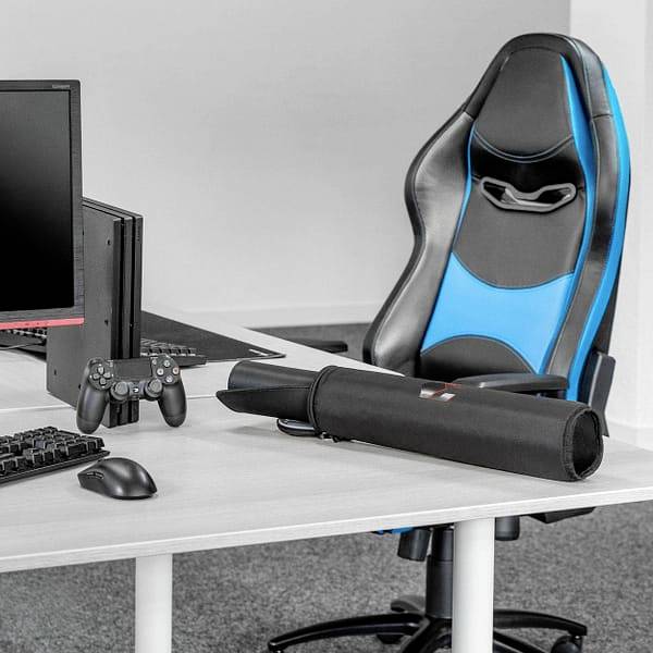 Gaming-Setup mit Monitor, Tastatur, Gamepad und Bürostuhl. Der Stuhl ist schwarz-blau, der Schreibtisch hellgrau, ideal zum Spielen.