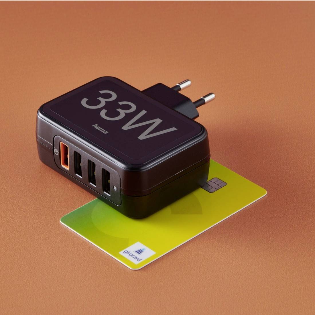 Ein 33W-Mehrfach-USB-Ladegerät mit vier Anschlüssen, darunter ein orangefarbener Schnellladeanschluss, liegt auf einer Karte.