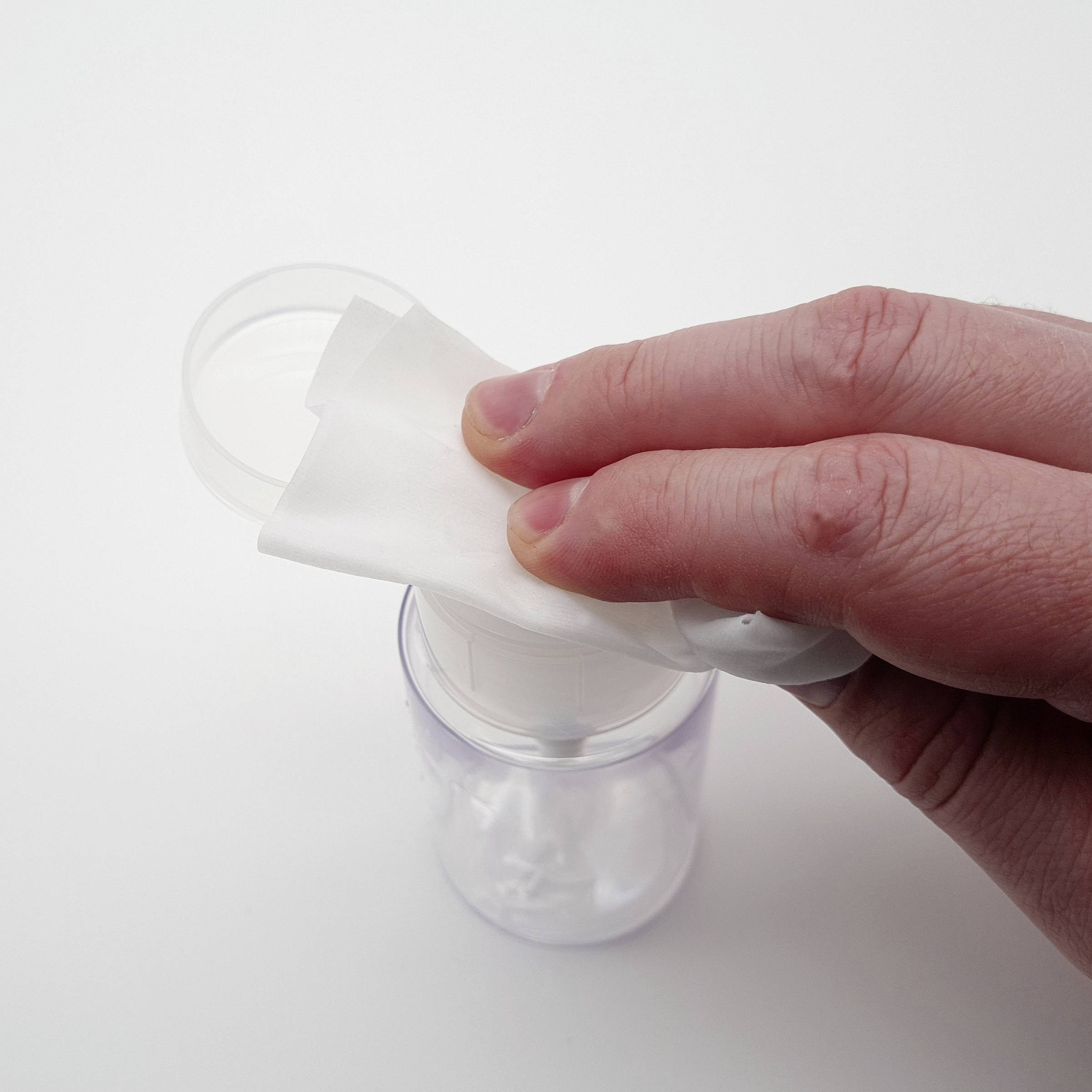 Eine Hand drückt ein Wattepad auf einen Seifenspender.