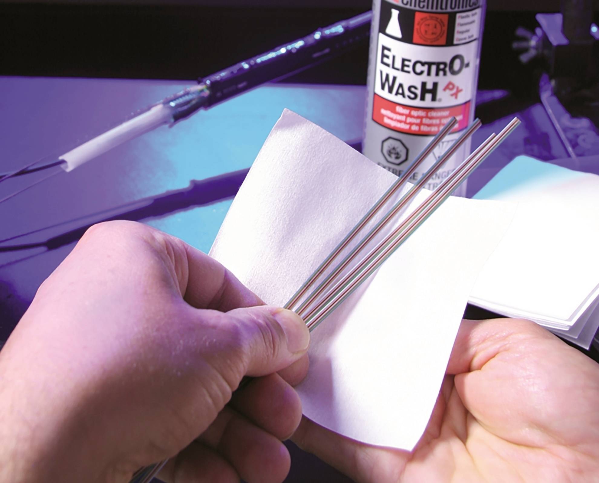 Zwei Hände reinigen metallische Stäbe mit einem weißen Tuch. Im Hintergrund steht eine Flasche mit der Aufschrift 'Electro-Wash'.