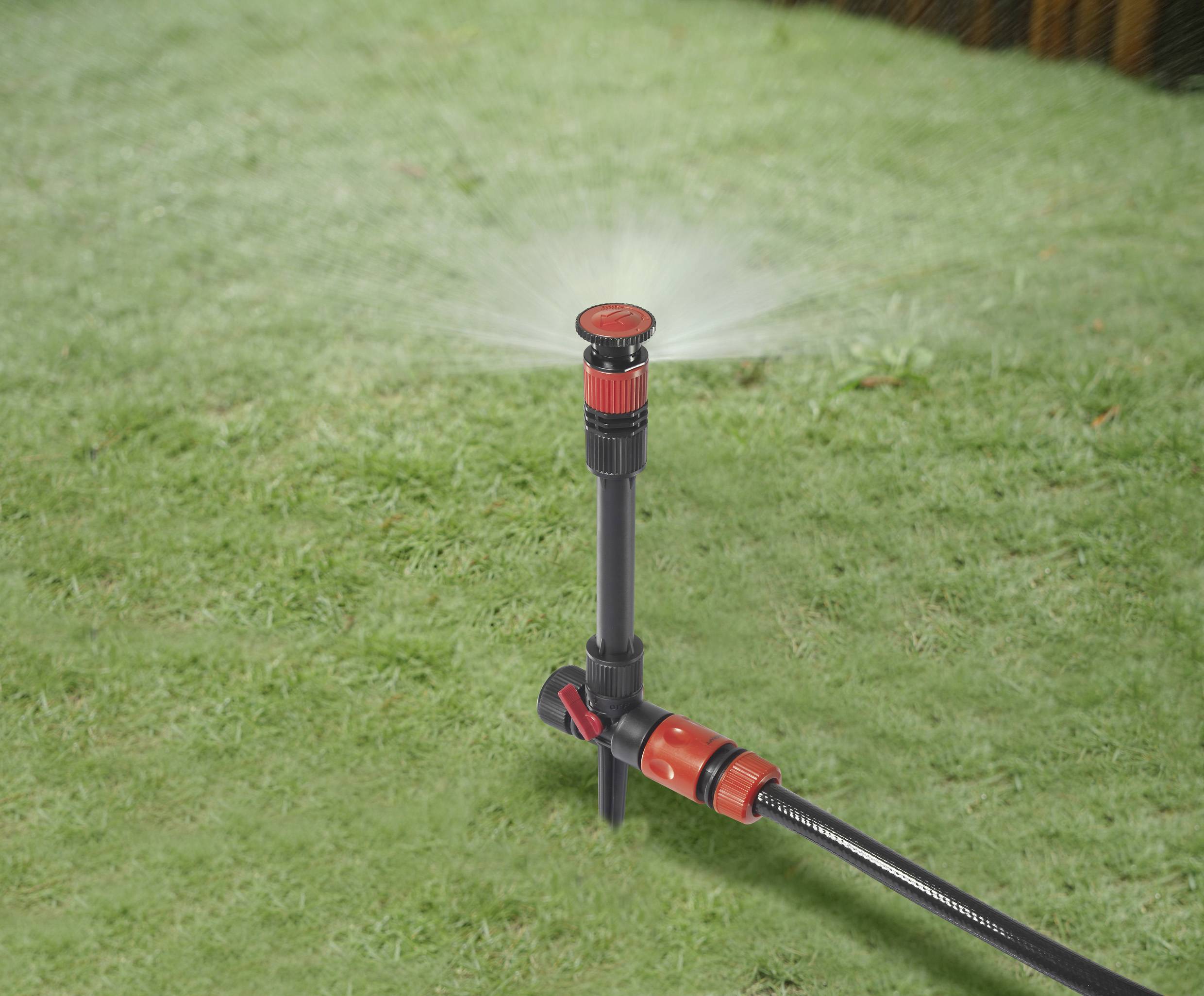 Rasensprenger auf grünem Gras verteilt Wasser in einer kreisförmigen Bewegung.