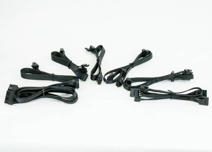 Mehrere schwarze Computerkabel unterschiedlicher Art und Länge auf weißem Hintergrund, einschließlich Strom- und Datenkabel.