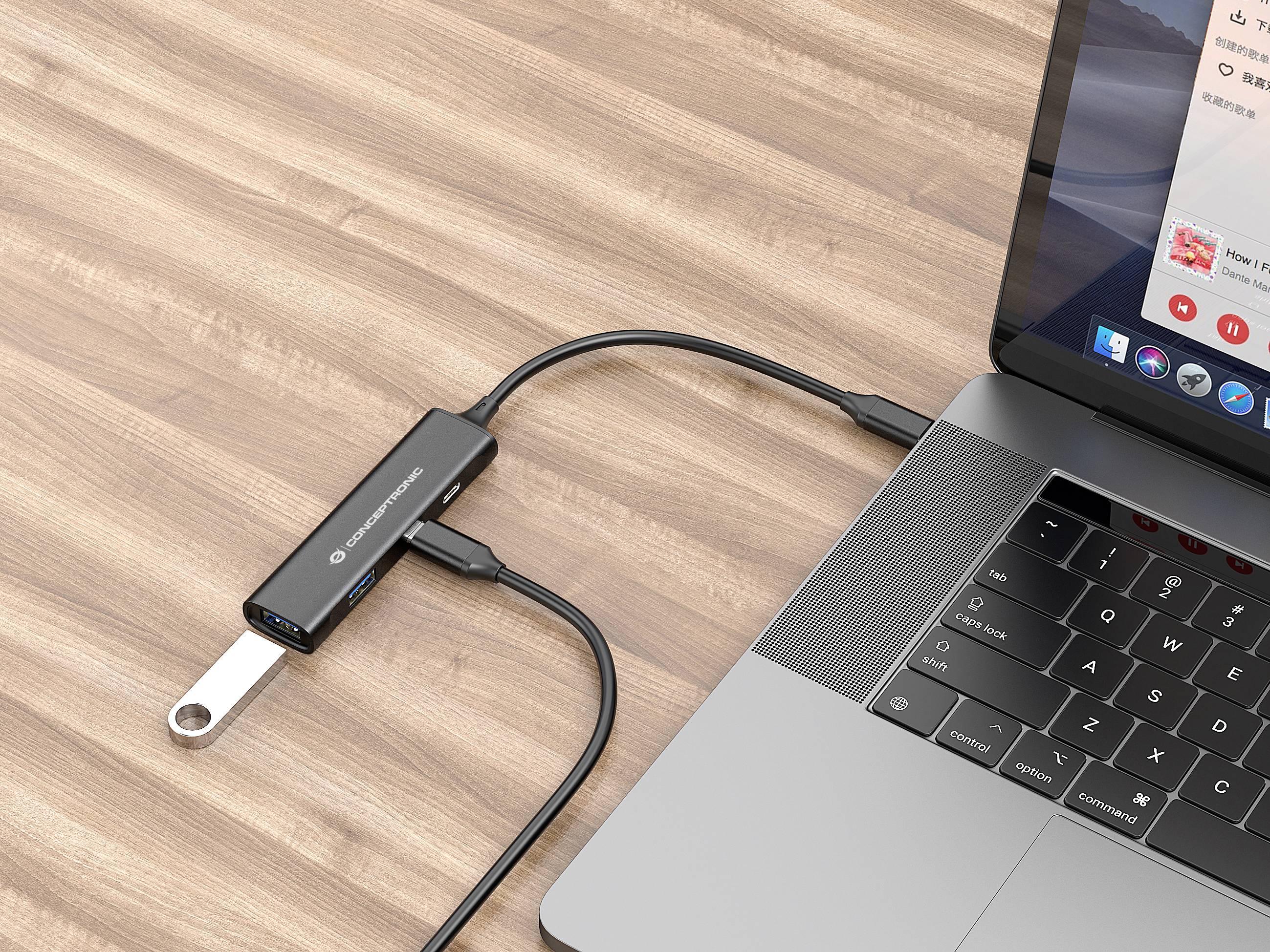 Ein Laptop ist über einen USB-C-Hub mit einem USB-Stick verbunden, der auf einem Holztisch liegt.