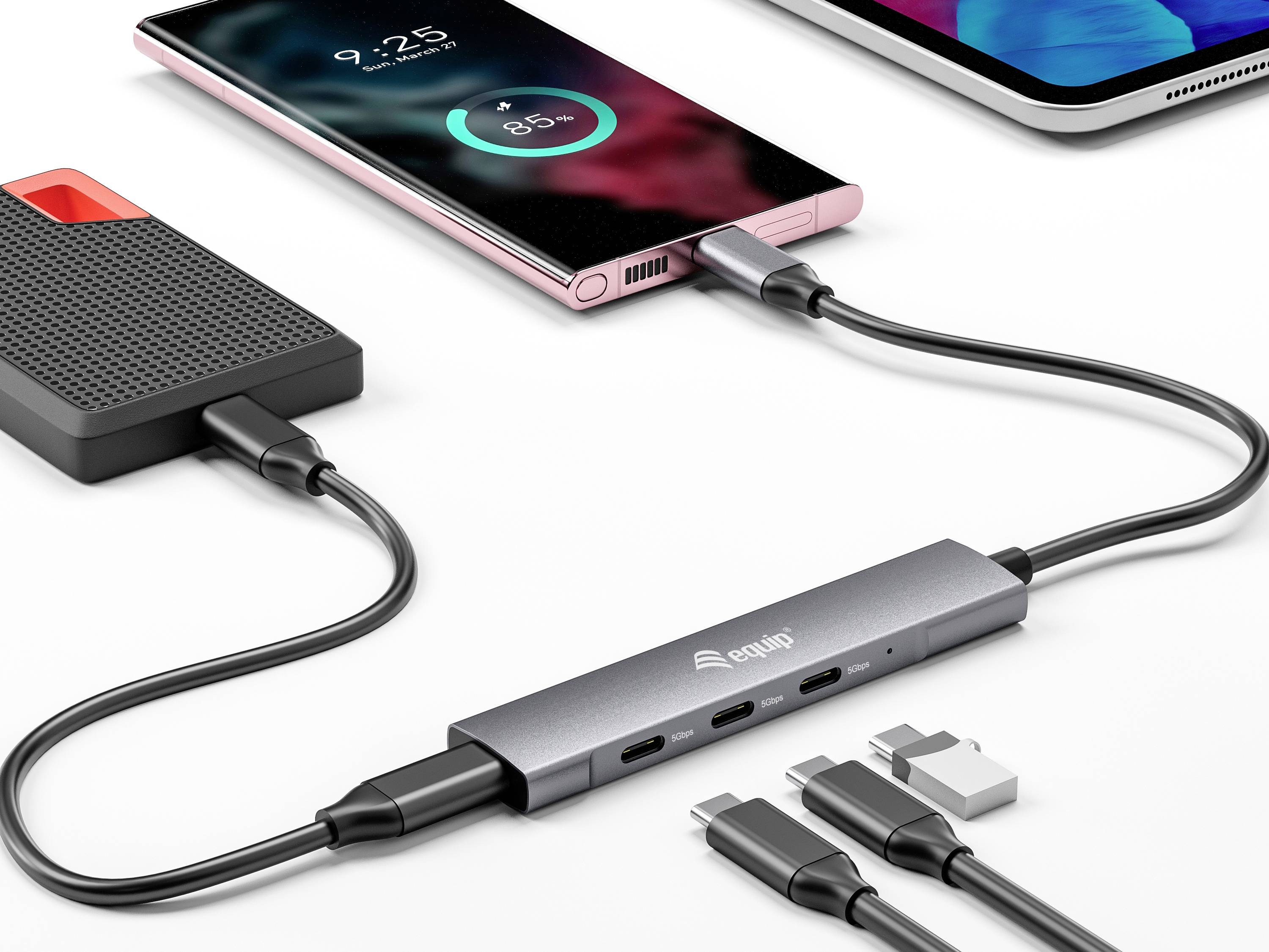 Ein Smartphone wird über einen USB-C-Hub aufgeladen, der auch mit einem externen Laufwerk verbunden ist. Prozentanzeige zeigt 85 % Ladung.