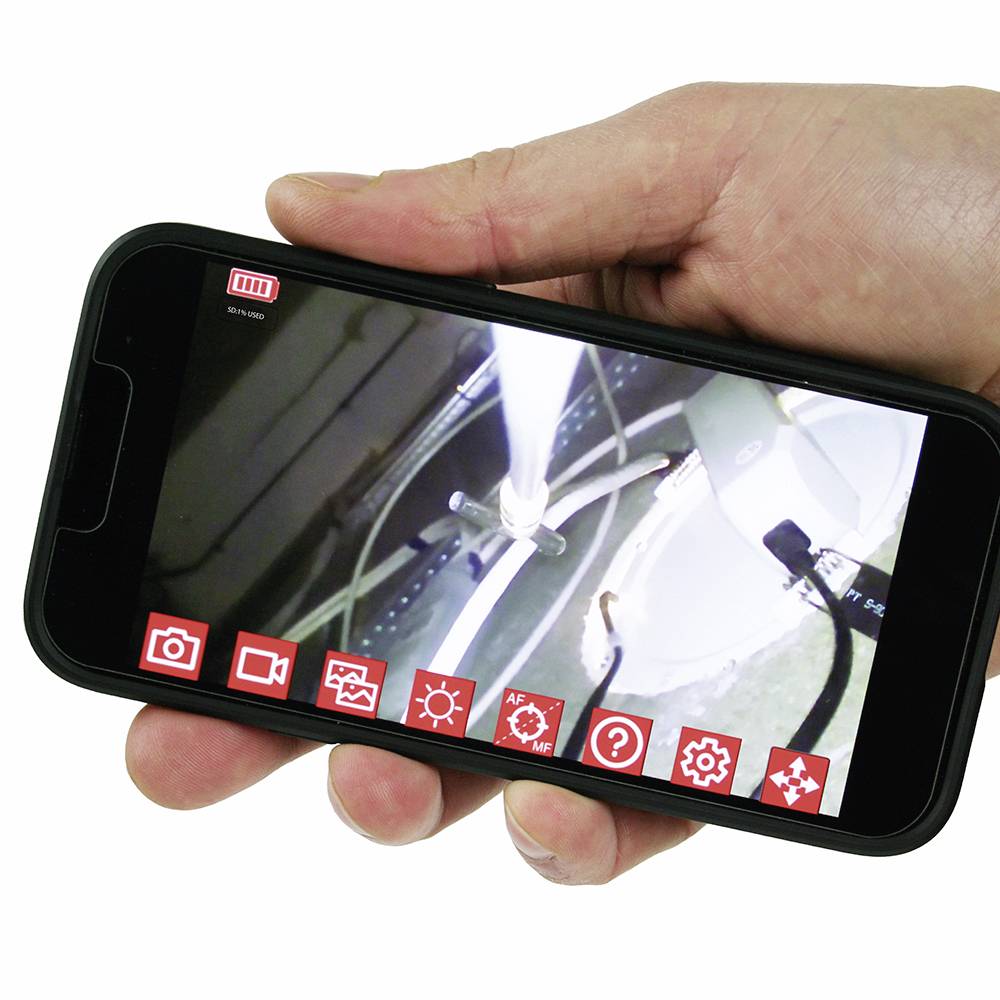 Eine Hand hält ein Smartphone, das eine Live-Videoaufnahme von einer technischen Maschine mit mehreren Symbolen auf dem Display zeigt.