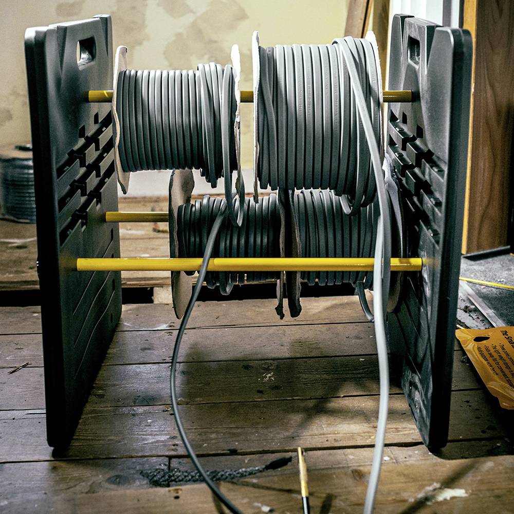 Spulen mit grauen Kabeln auf einem Holzständer, organisiert und bereit für den Einsatz in elektrischen oder handwerklichen Arbeiten.