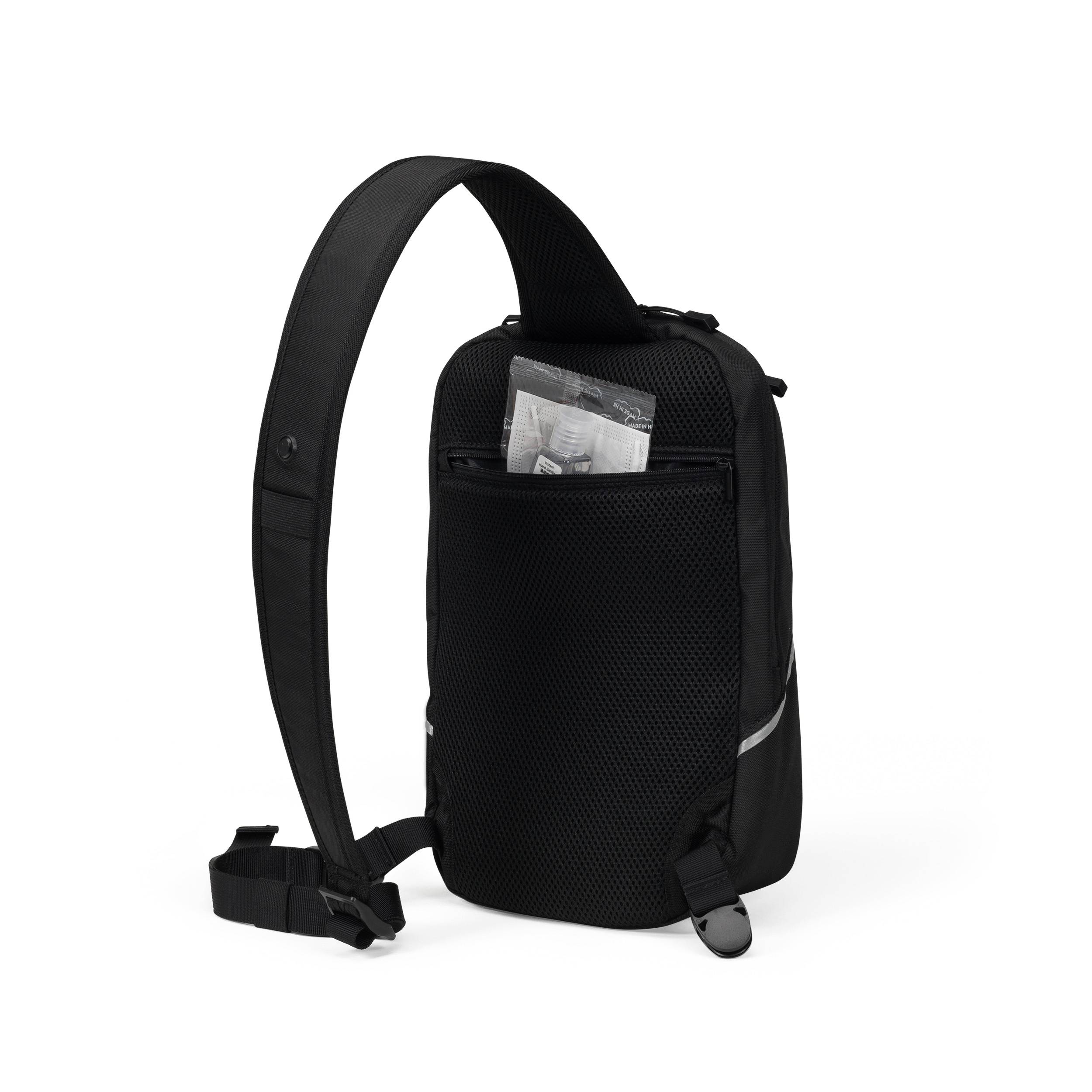 Eine schwarze Schultertasche mit einem einzigen Gurt. Sie hat eine vordere Netztasche mit sichtbar eingestecktem Inhaltspapier.