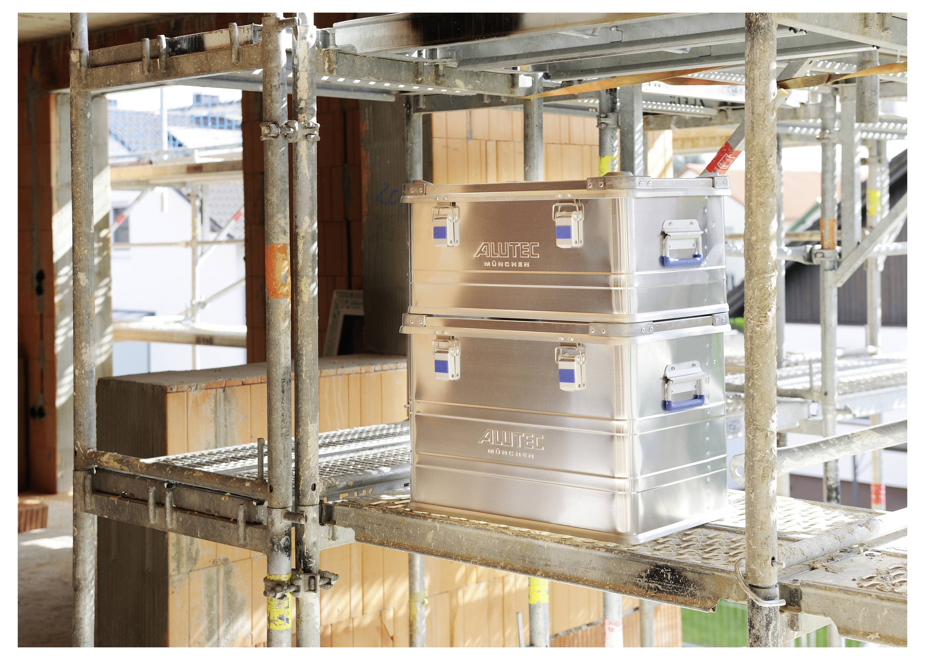 Stahlkisten, die auf Baugerüsten gestapelt sind, mit sichtbarem Baumaterial und Stahlkonstruktion in der Umgebung.