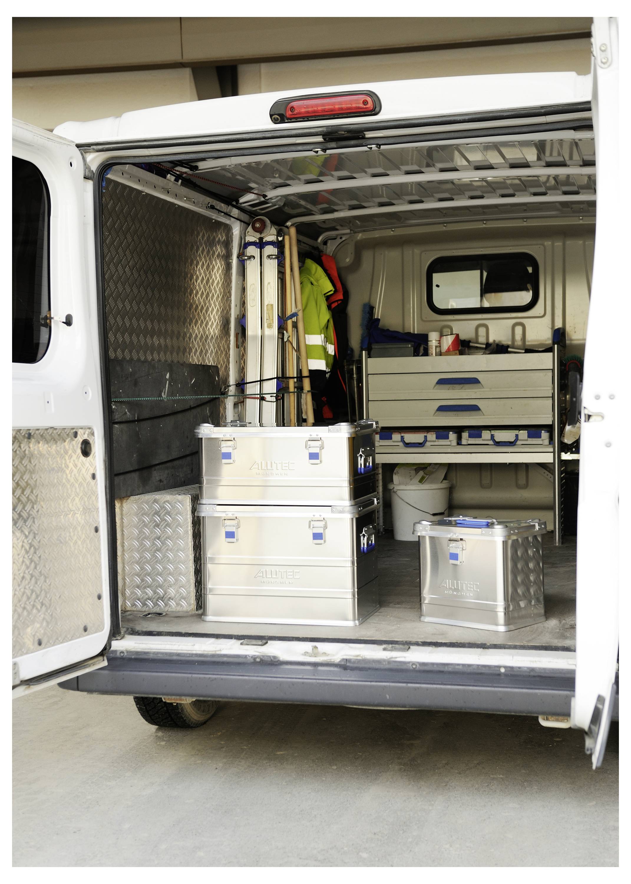 Die Rückseite eines Lieferwagens ist offen und zeigt organisierte Metalllagerkästen, Werkzeuge und Ausrüstung im Inneren.