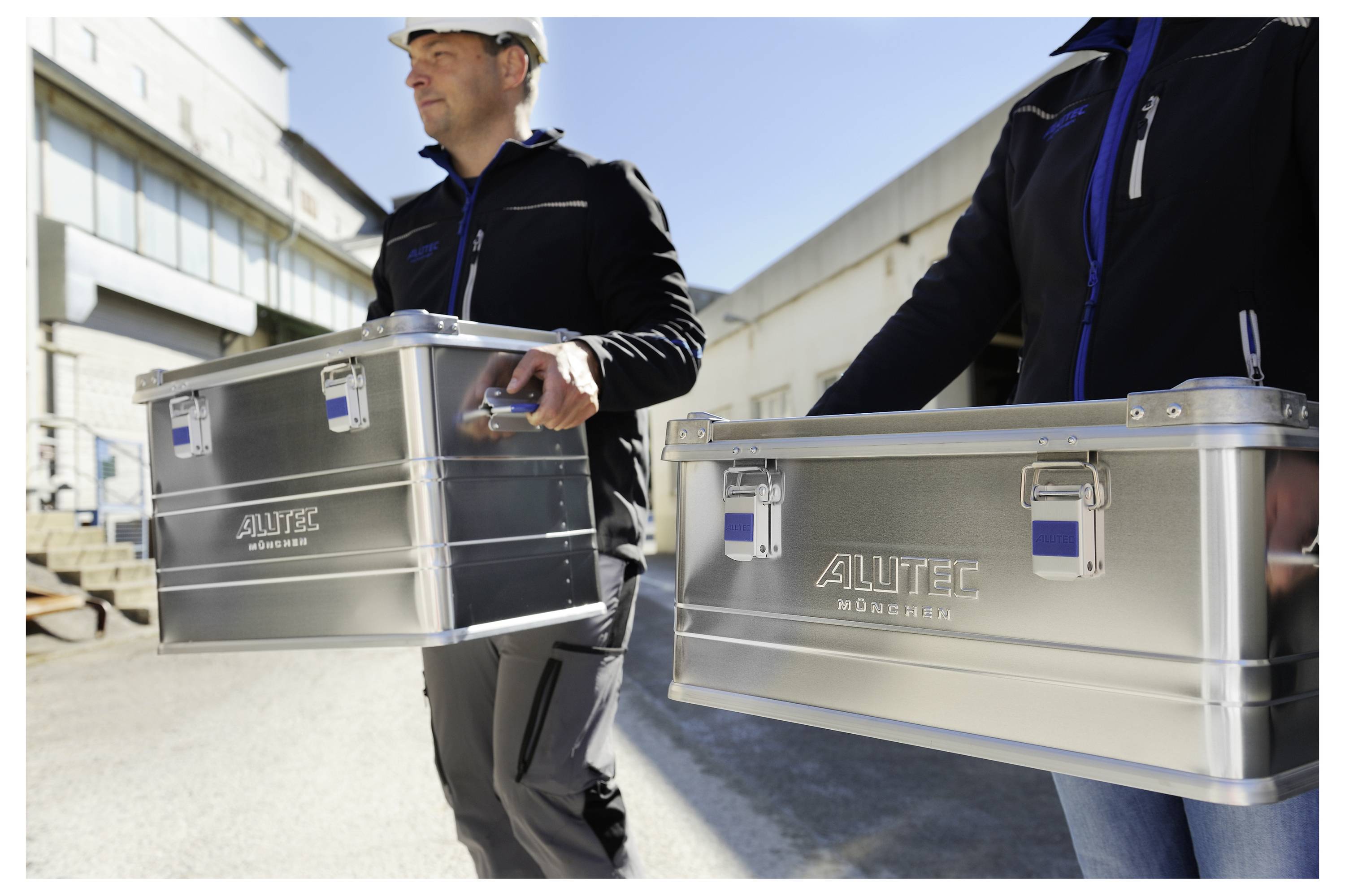 Arbeiter tragen zwei Metallboxen mit der Bezeichnung „Alutec