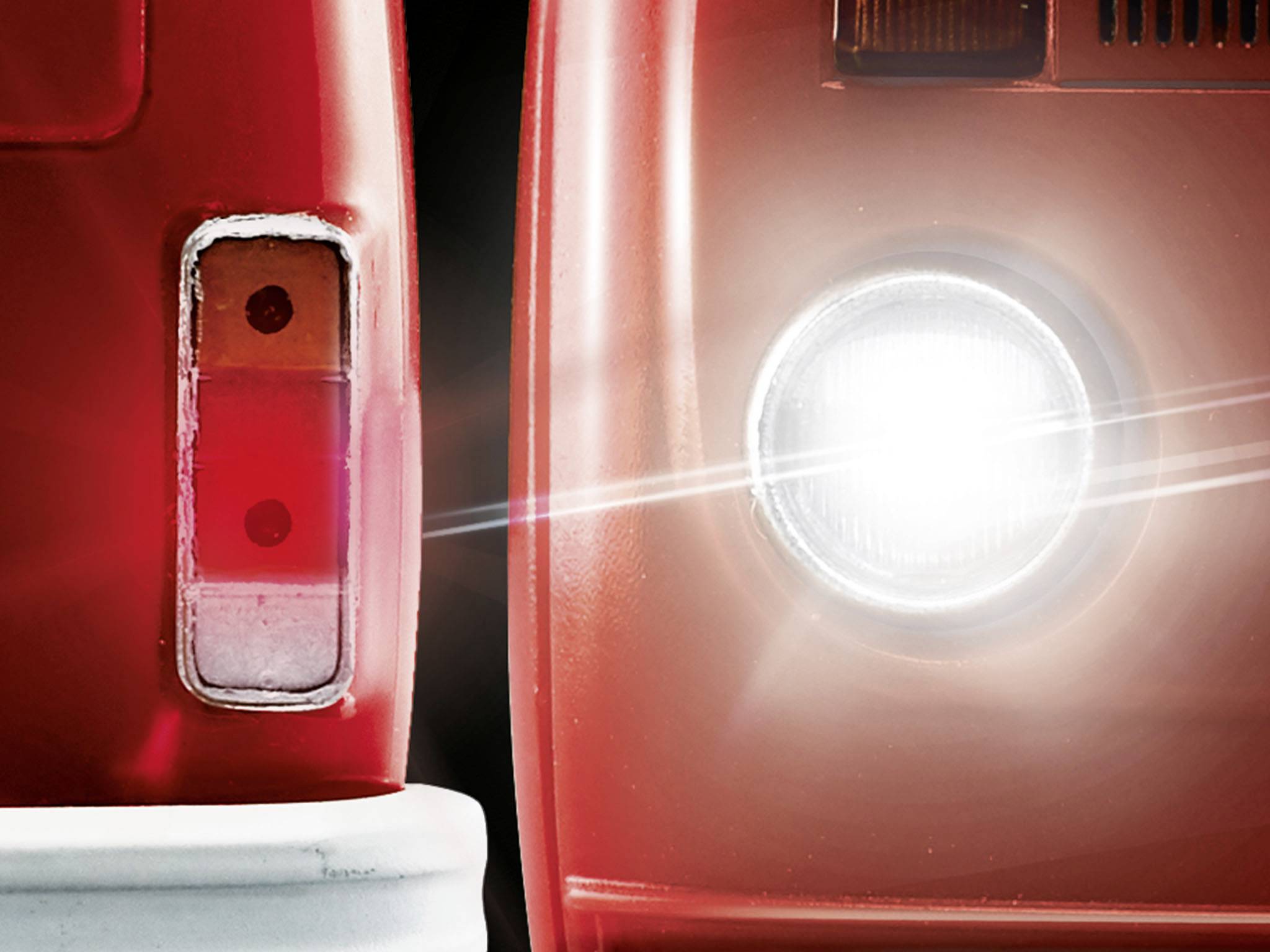 Nahaufnahme eines roten Oldtimer-Autos mit Scheinwerferlicht. Links ist der hintere Teil und rechts der vordere Teil zu sehen.