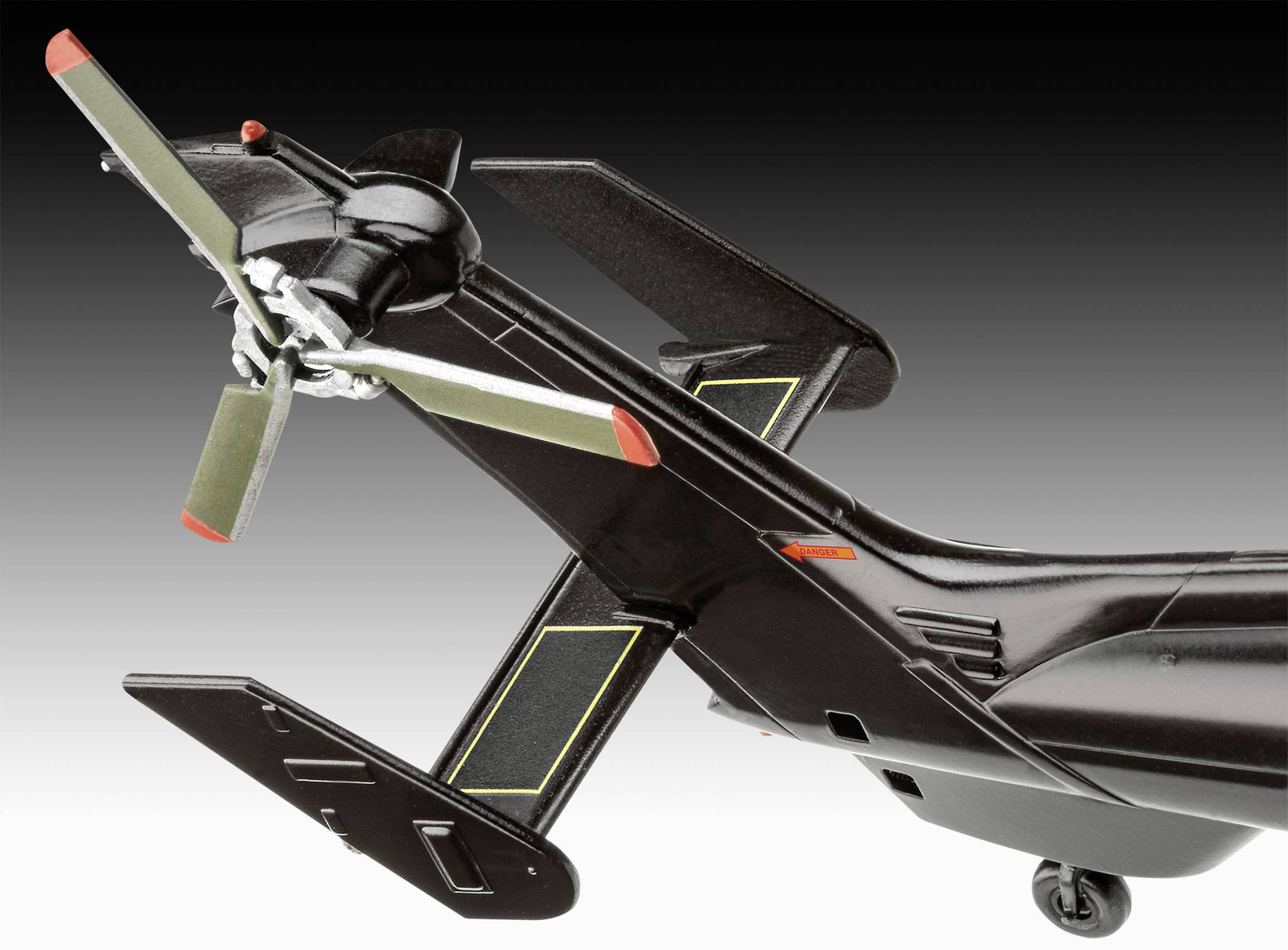 Ein Modellhubschrauber mit Doppelschraube am Heck vor einem schwarz-weißen Hintergrund, zeigt hohe Detailgenauigkeit und Bauweise.