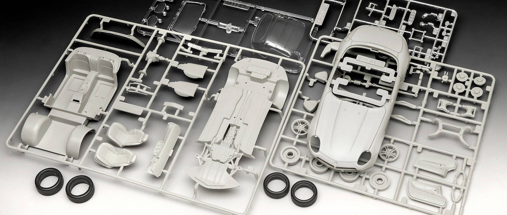 Bauteile eines Modellauto-Bausatzes, einschließlich Karosserie, Räder und sonstiger Teile, organisiert auf Kunststoffspritzrahmen.